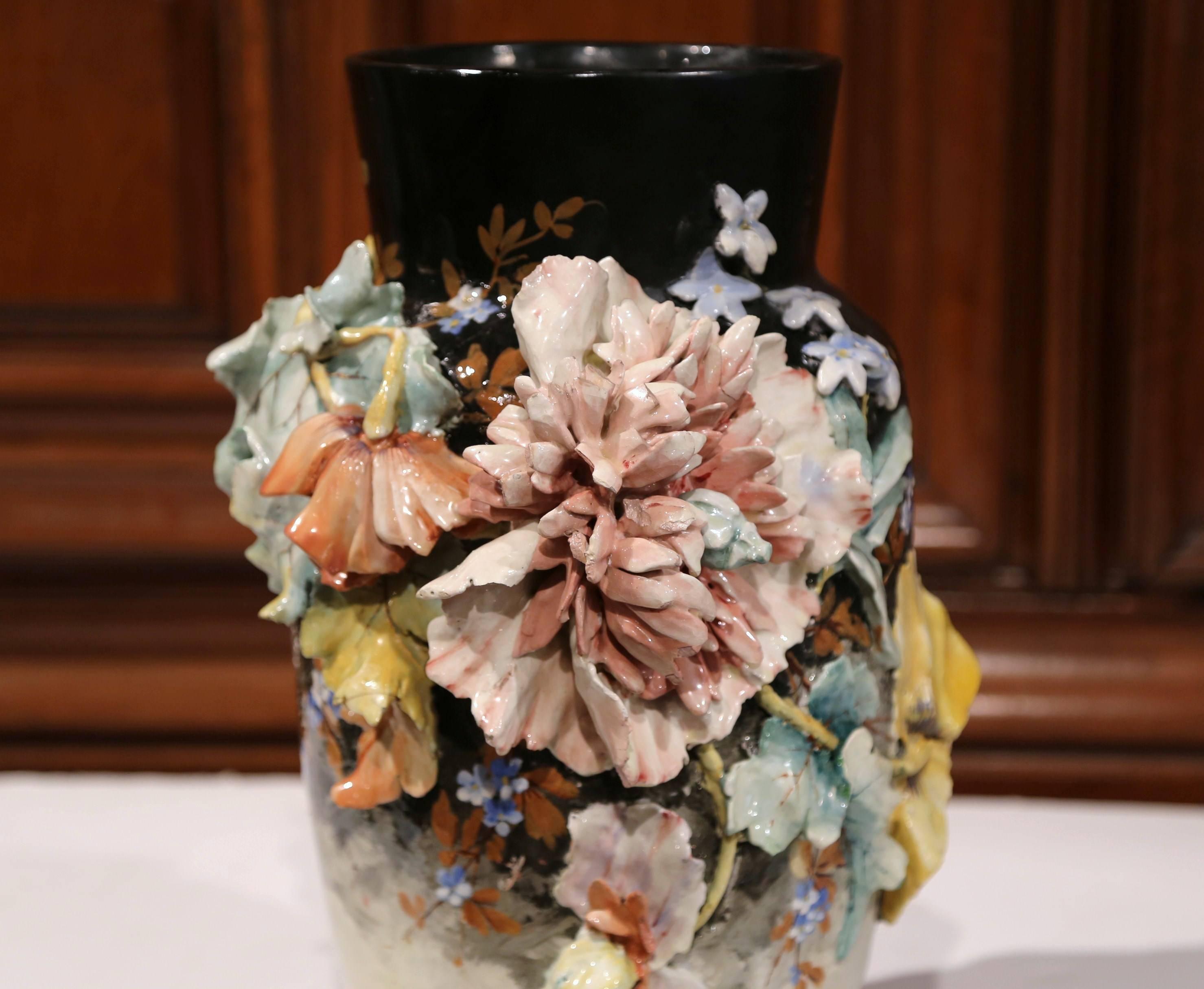 This beautiful, hand painted Majolica vase was sculpted in Montigny sur Loing, France, circa 1870. This colorful black, grey and white ceramic planter is decorated with high relief large flowers in a pink, orange and yellow palette and embellished