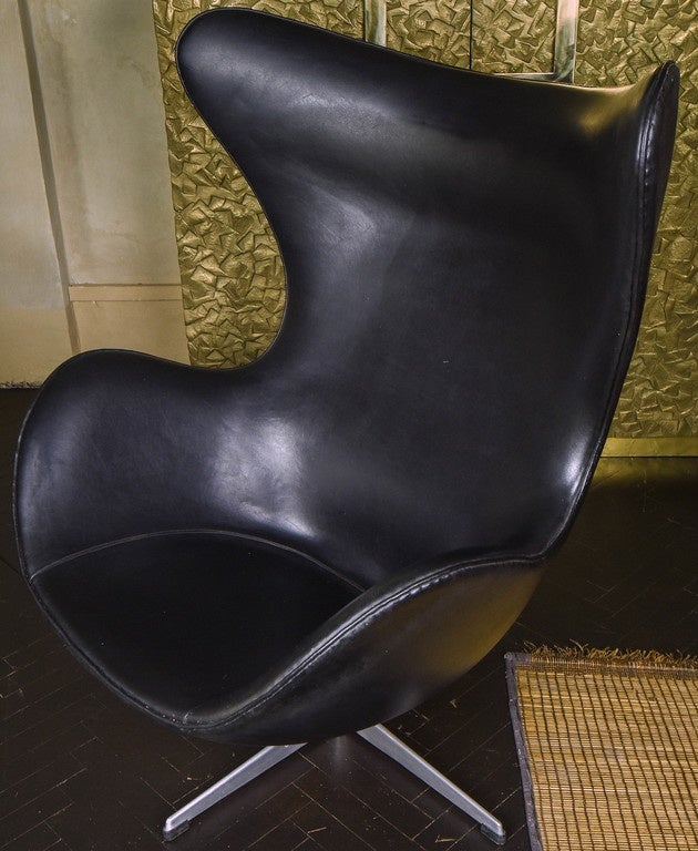 Jacobsen's iconic modern wingback chair designed for the SAS hotel in Copenhagen, one-piece cast aluminum base and the chair retains the original black leather with a beautiful vintage patina from age and use, as showed on the last image the chair