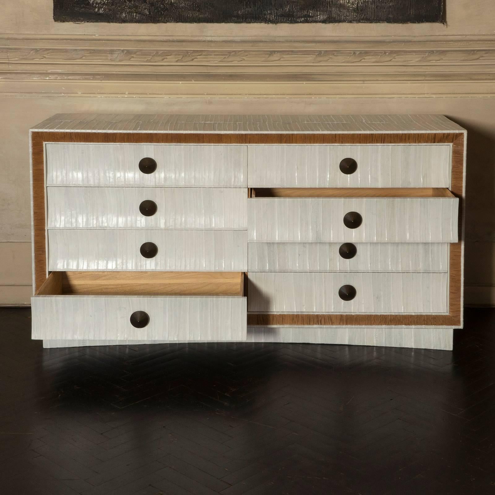 Natural oak eight drawers chest, newly covered in ivory eel skin, also each drawer as a padded eel skin base, original combed oak border and conical brass hardware.