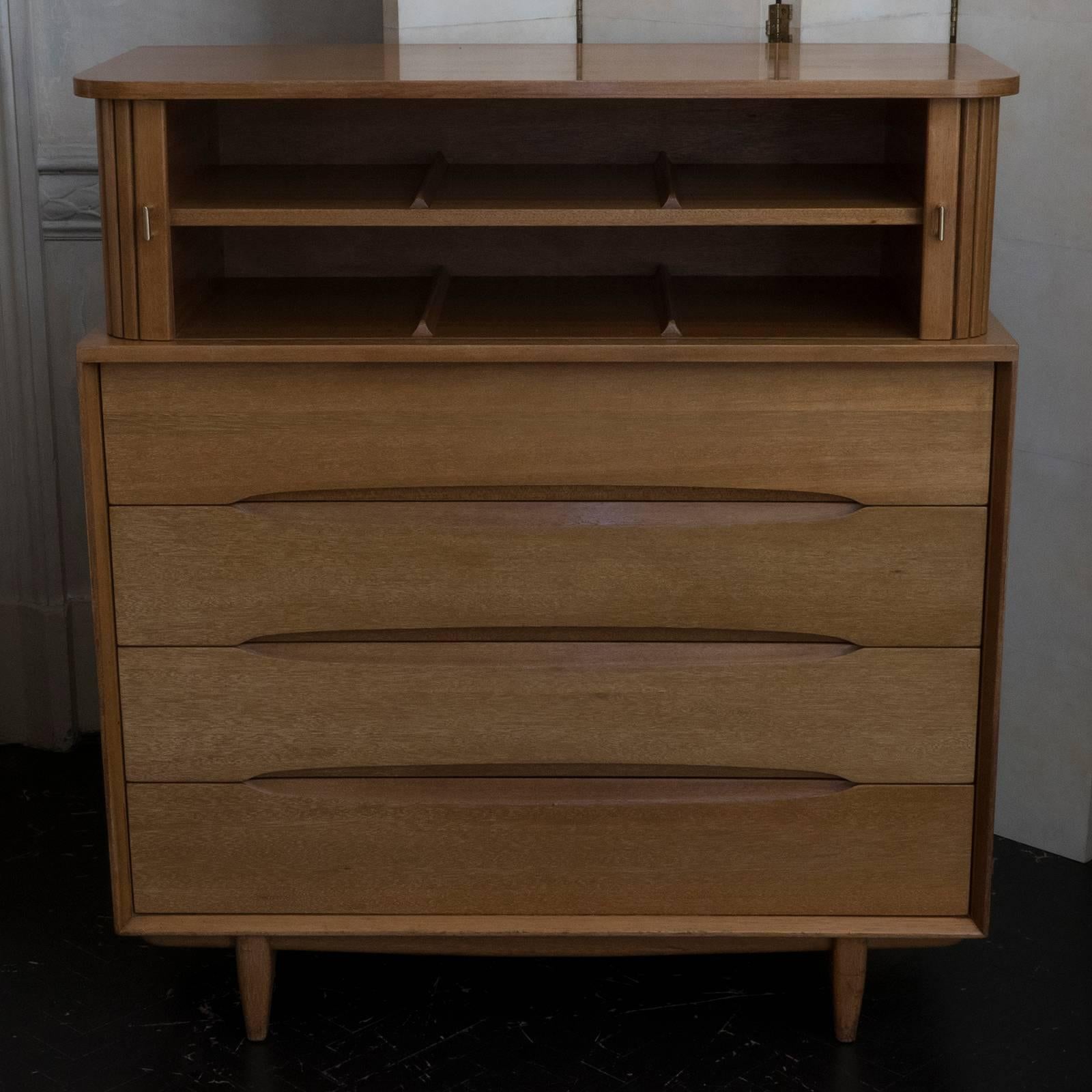 Tall chest in mahogany for Brown Saltman, 1950s. Four sculpted drawers, shelve behind tambour doors with brass pulls on top.