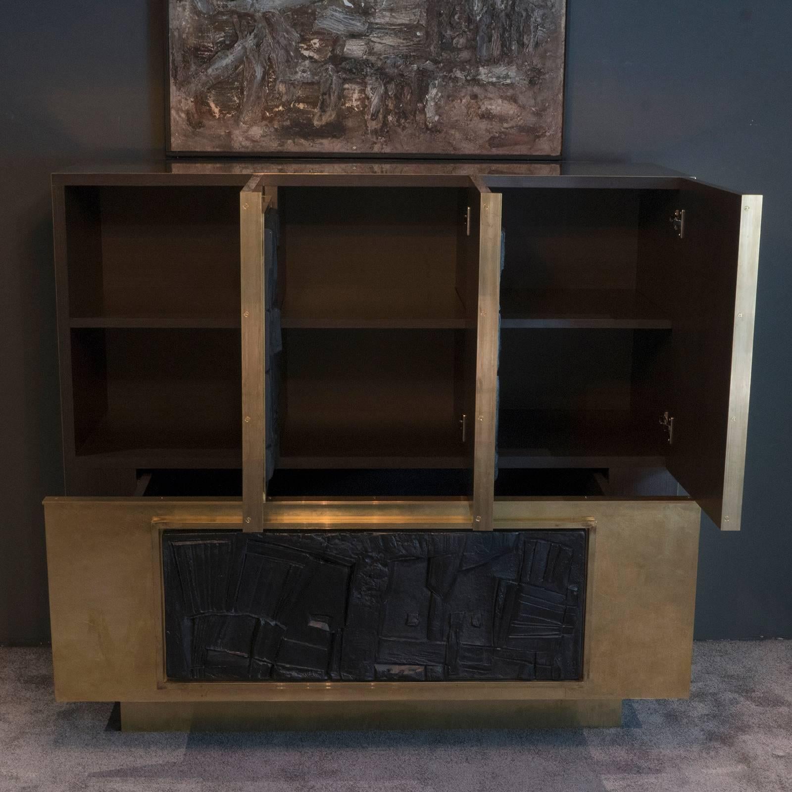 Sideboard entirely covered with unvarnished brass for a vintage look, the sculptural plaster panels are from the French artist Roger Desserprit Atelier, the inside shelves are not adjustable.