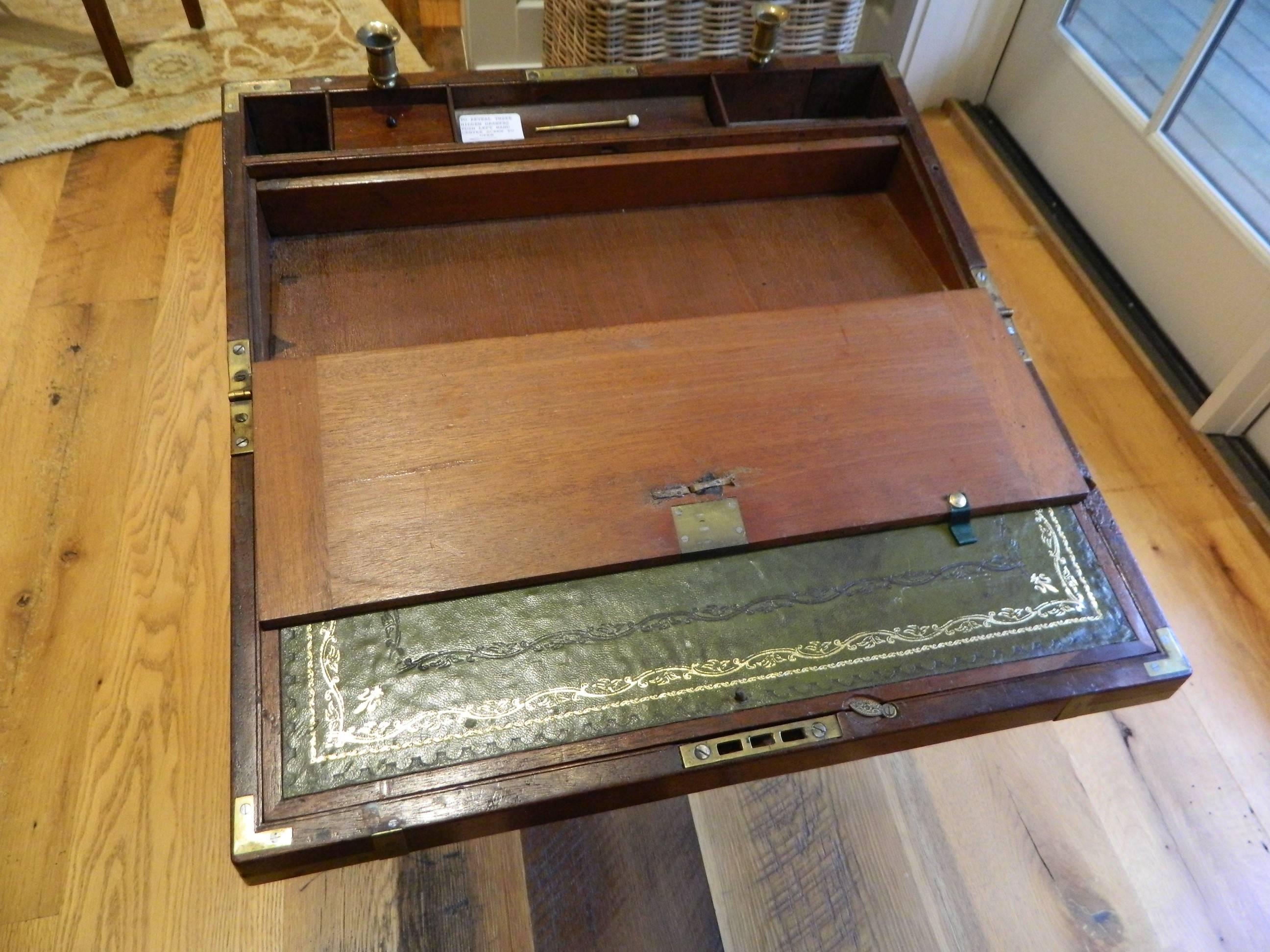 English mahogany lap desk on a custom-made stand with brass fit decorations and candle holders, 19th century. Desk opening to reveal a writing surface and storage compartments.
