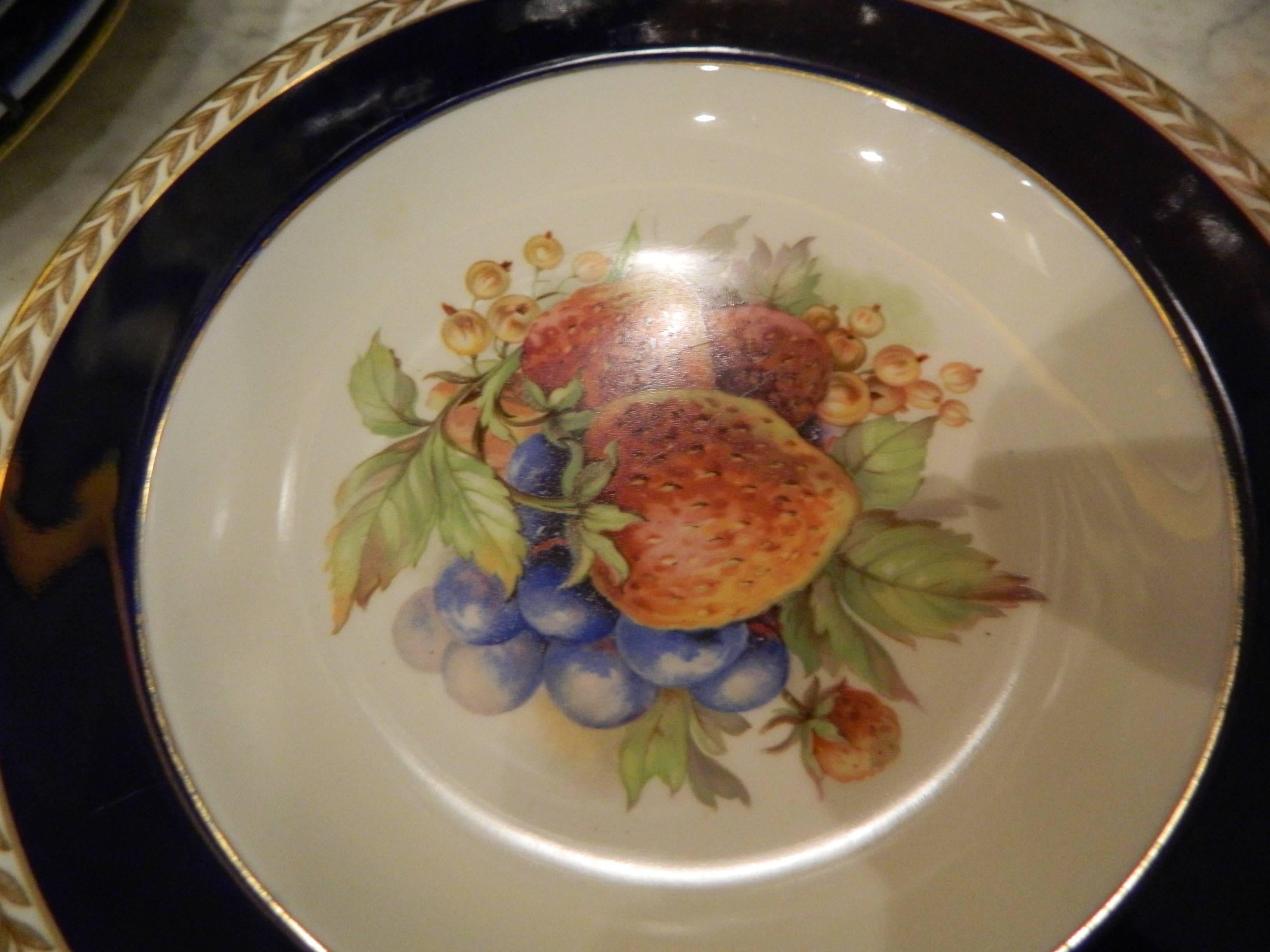 Set of seven Crown Ducal dessert plates, 20th century. Made in England. Cobalt blue rim luncheon plate with a gold laurel rim. Peaches and grapes motif center.
