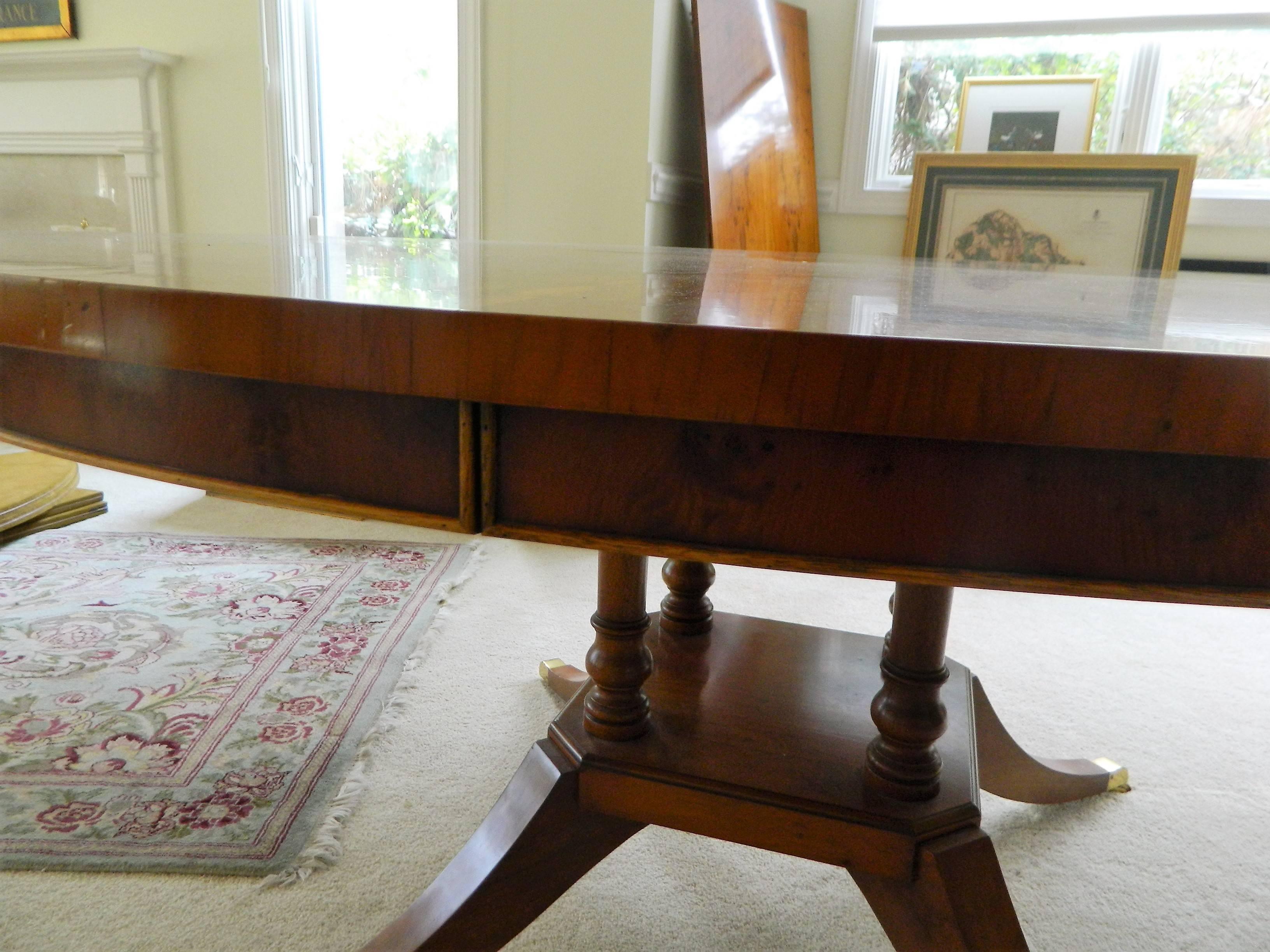 Custom-made, English, yew wood, sunburst dining table with apron and two Leaves. It rests on quad turned columns with platform and splayed legs ending in brass toecaps and casters, early 20th century. Dimensions with no leaves: 29.75" height x