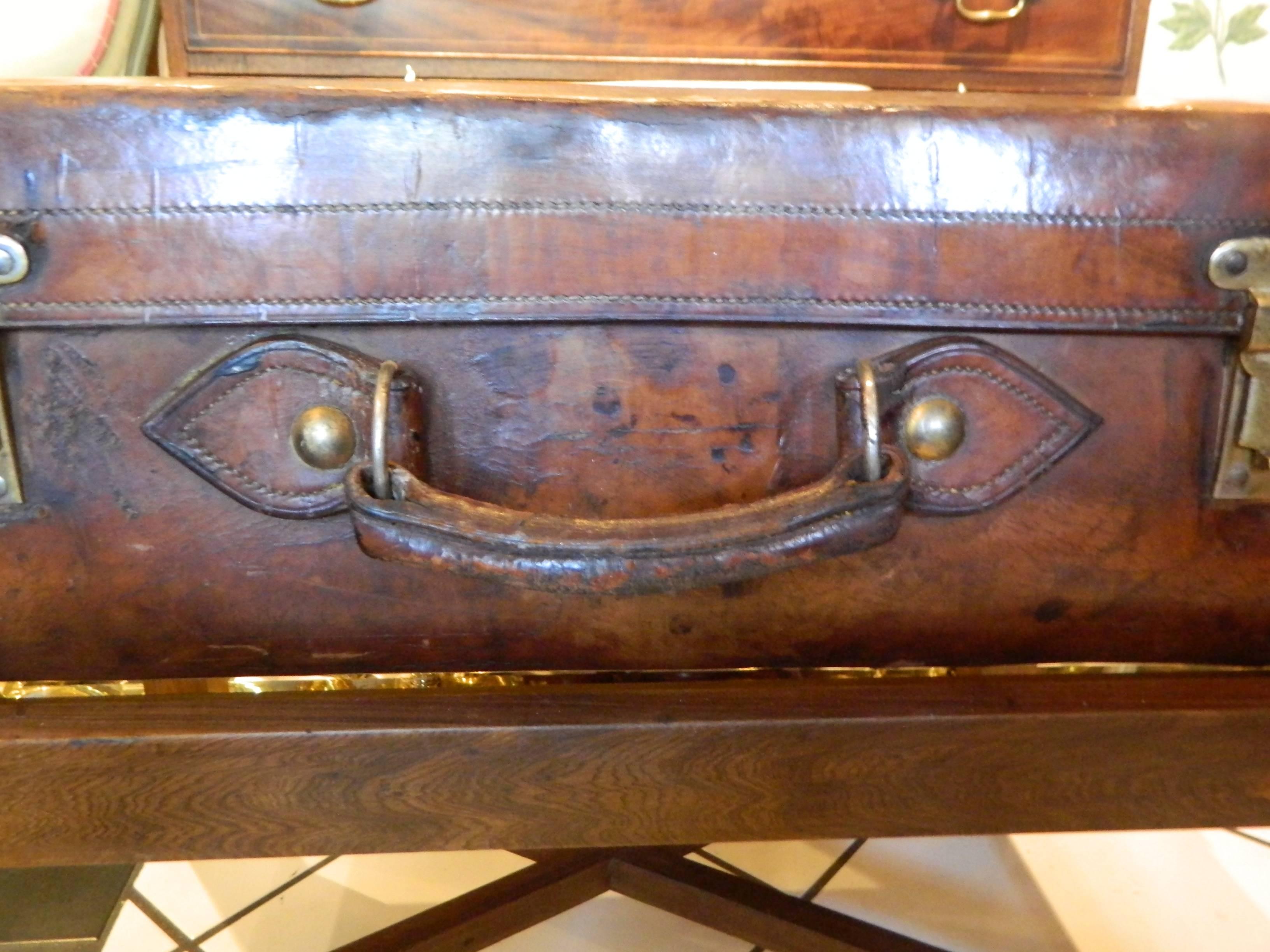 Valise anglaise en cuir transformée en table basse sur pied, 19e siècle.