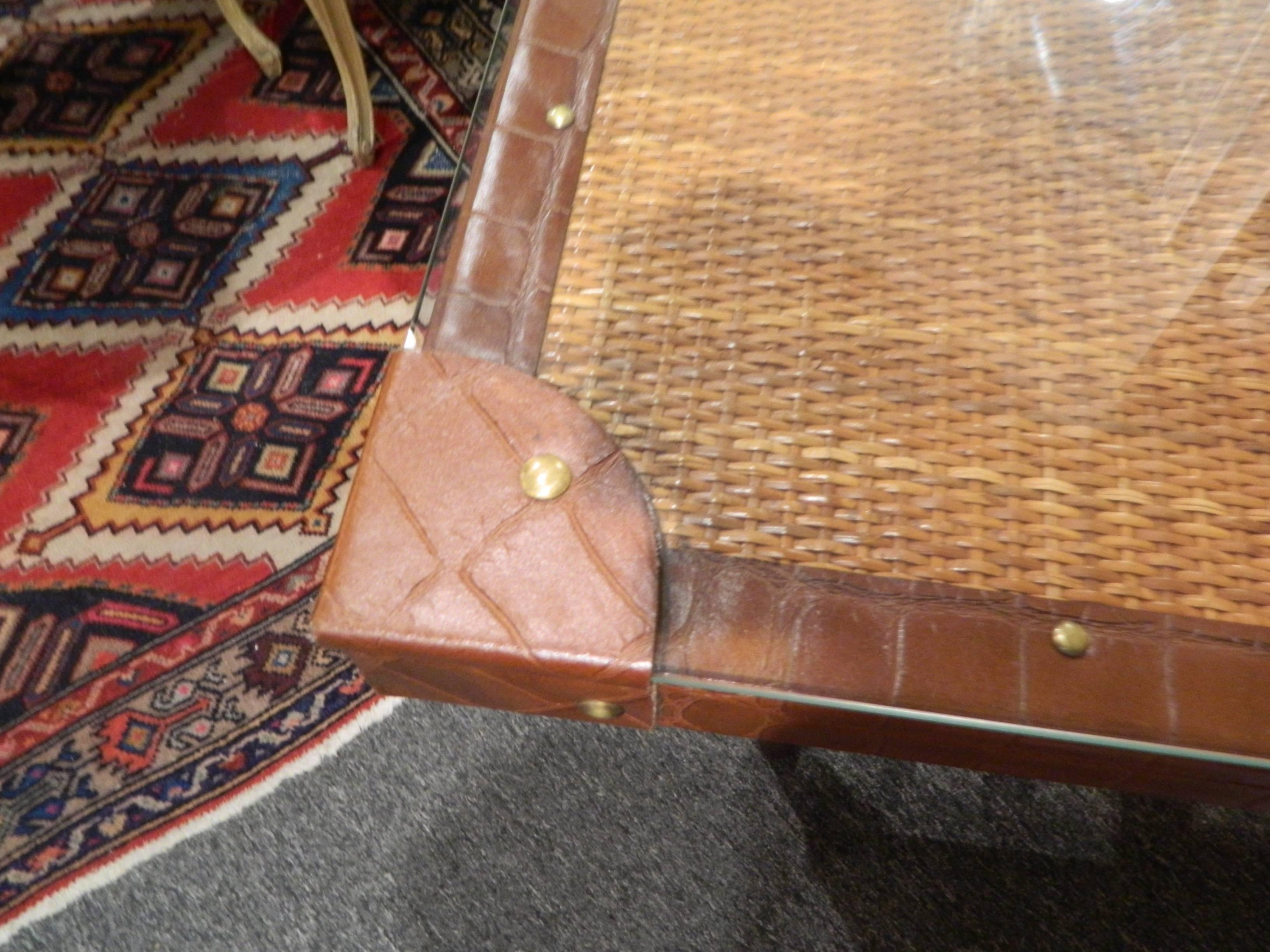 Rattan with leather and brass accents and mahogany base games table, 20th century. Glass top included.
  