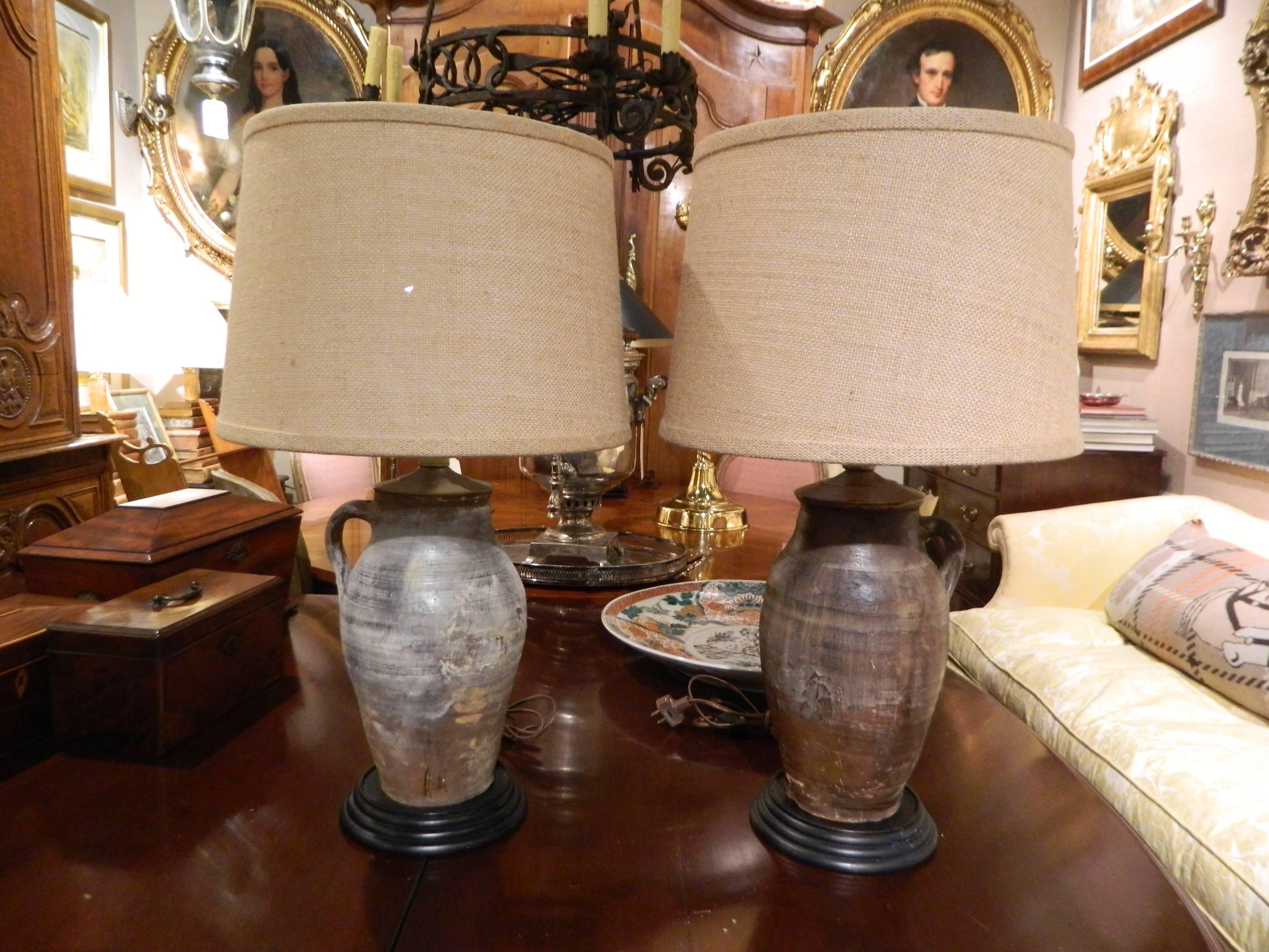 Pair of Italian terracotta oil jars with single handles and adapted as lamps, 19th century. Fitted with burlap shades.
 