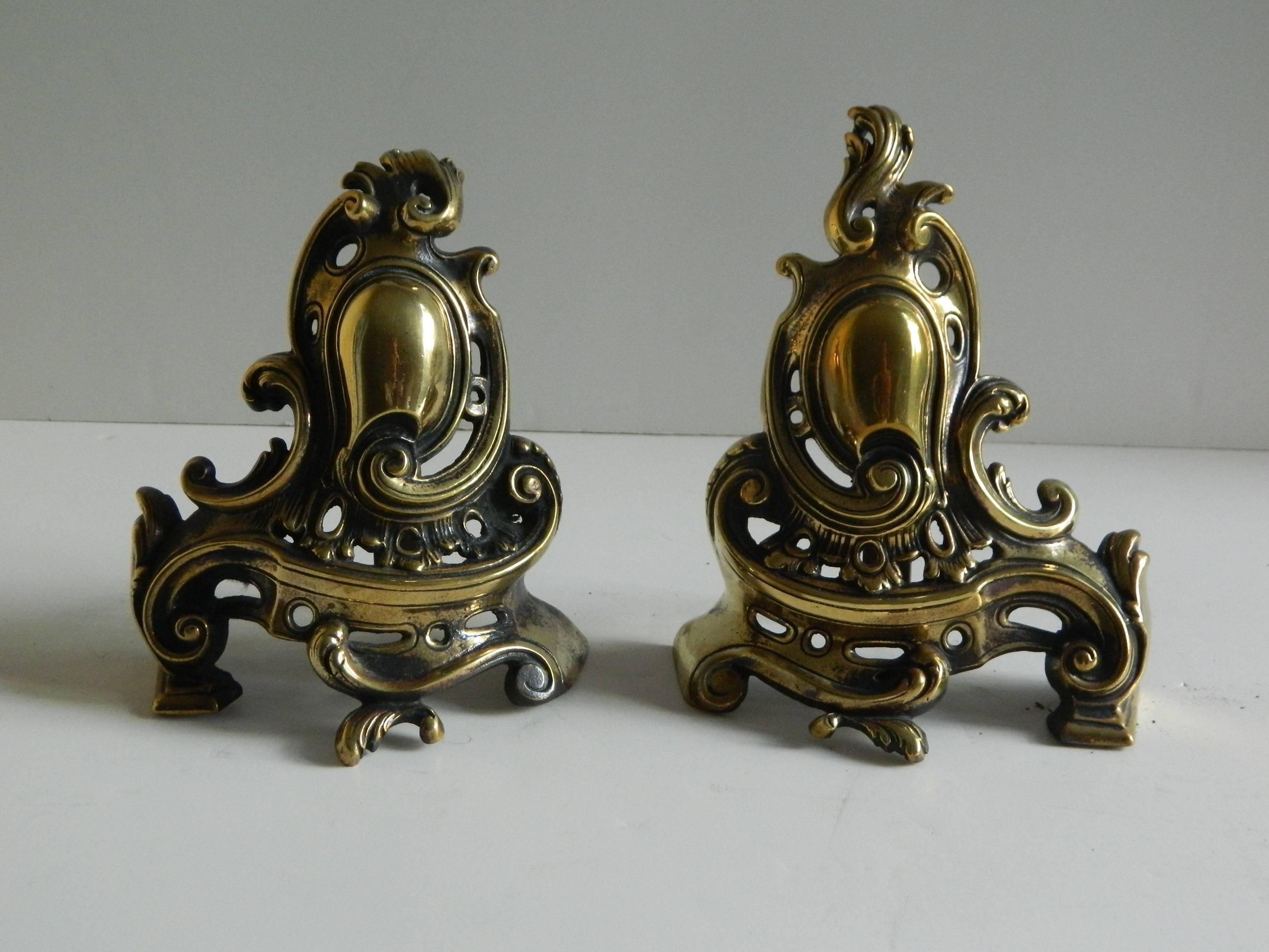 Pair of brass small chenets or andirons with shield and scrolls, 19th century.
   