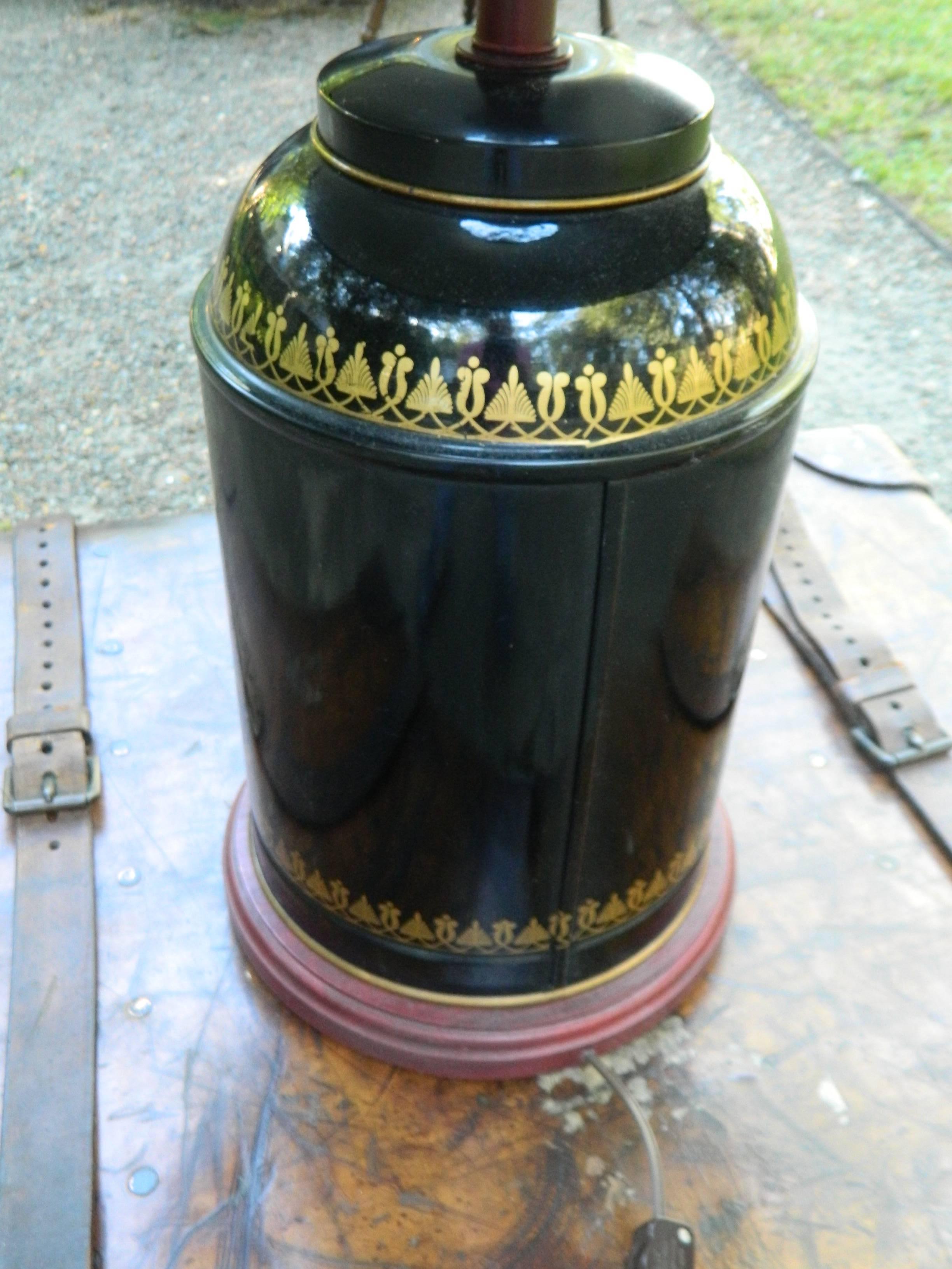 Pair of black tole canisters adapted as lamps with a coat of arms design, 20th century.
 