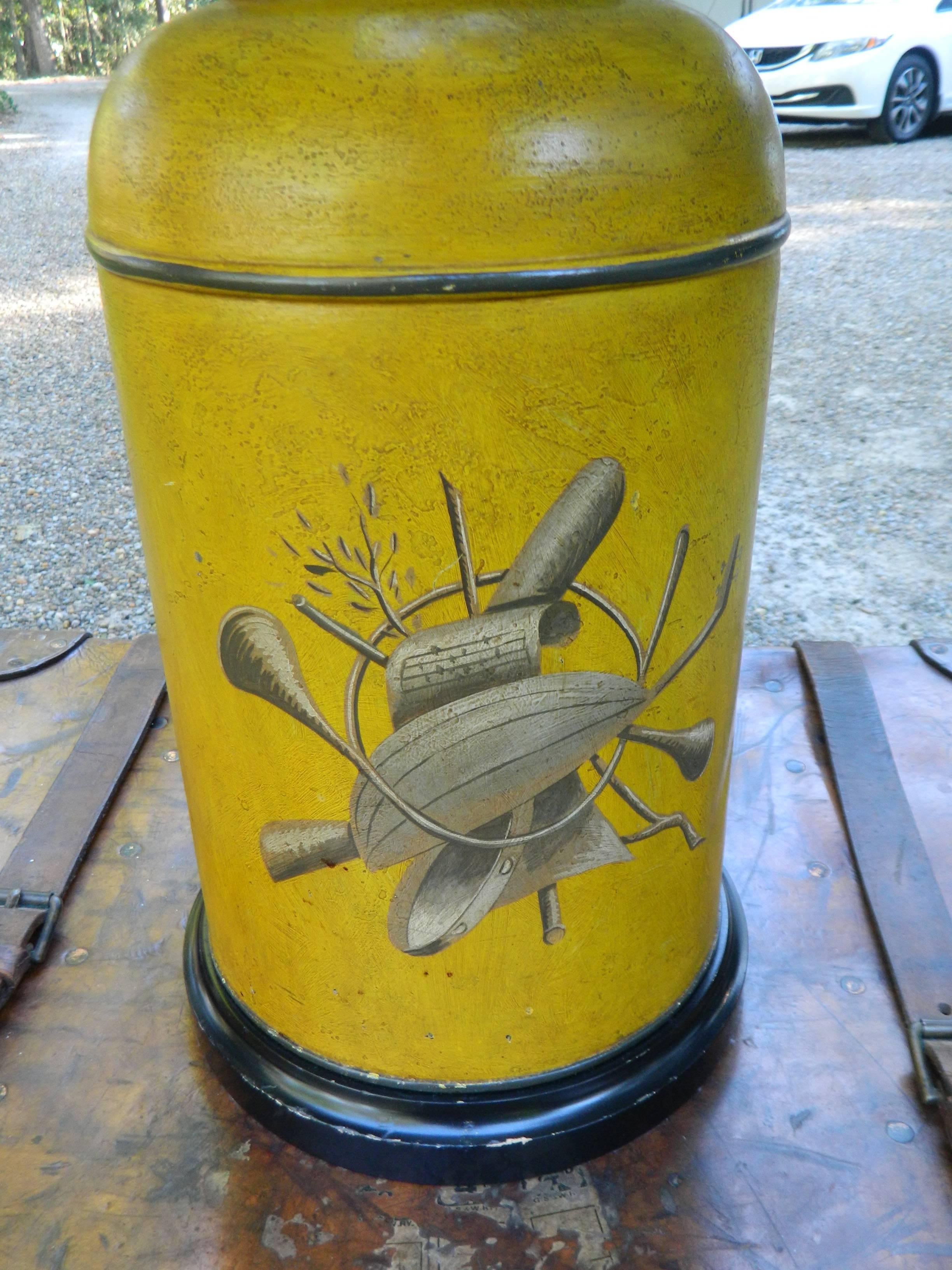 Tole canister in a mustard color with a painted musical scene, 20th century.
  