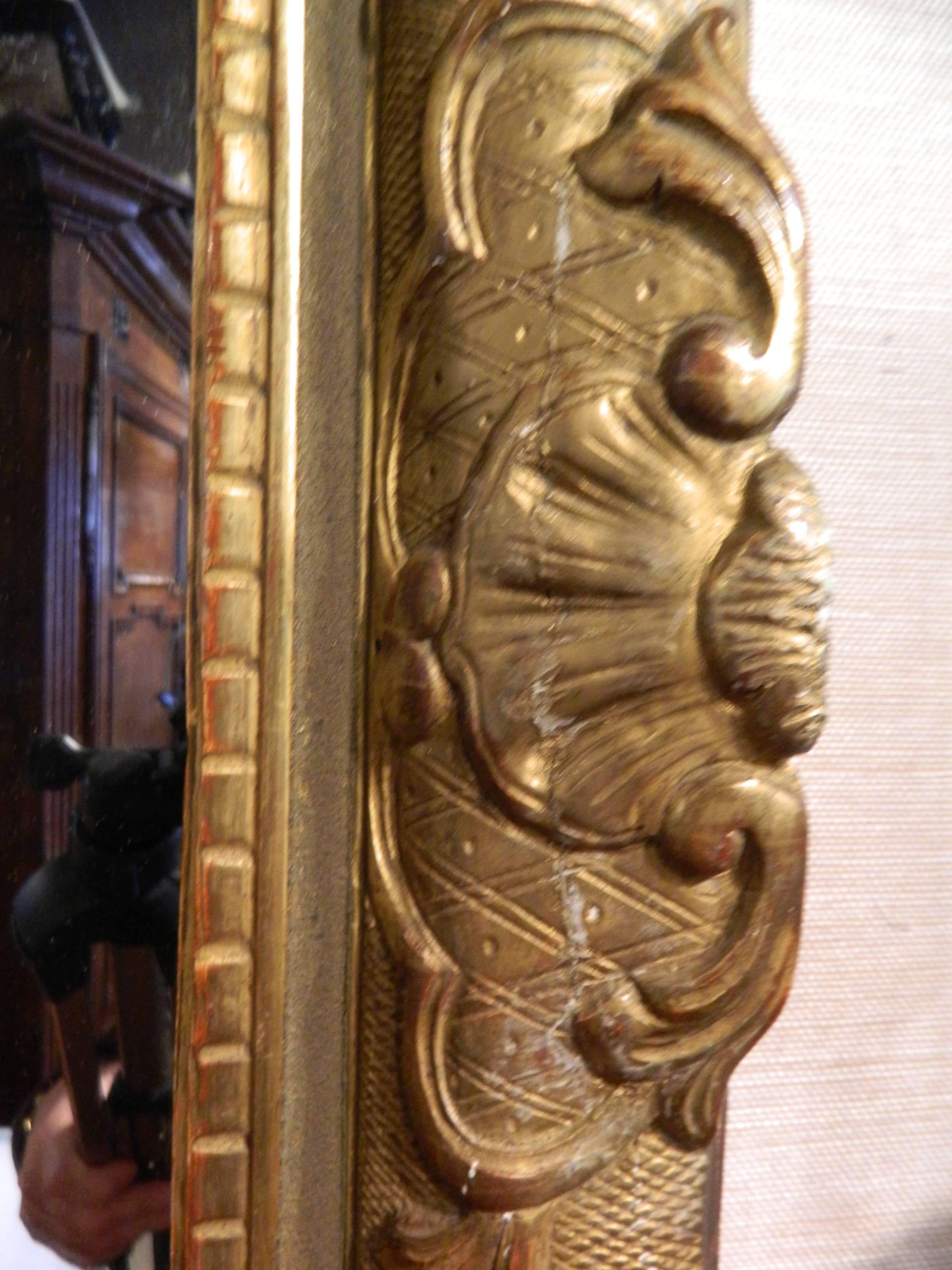 Italian gilt gesso mirror, 18th century, the arched rectangular mirror plate surmounted by a pierced rocaille crest, the mirror plate surround carved with shells and scrolling foliage.