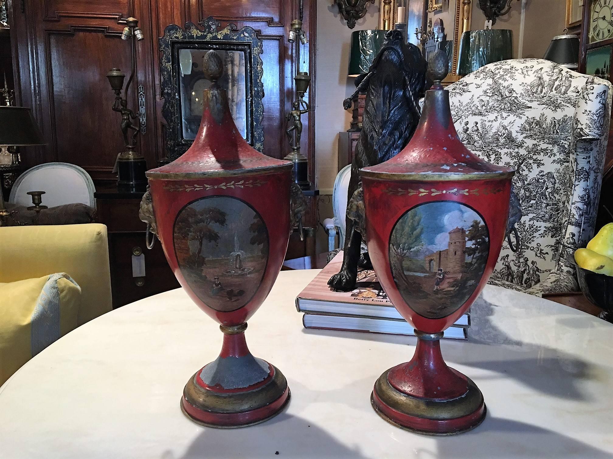 Pair of Regency painted lead covered urns, 19th century. Having a red ground with oval cartouche depicting an Italianate landscape.
          