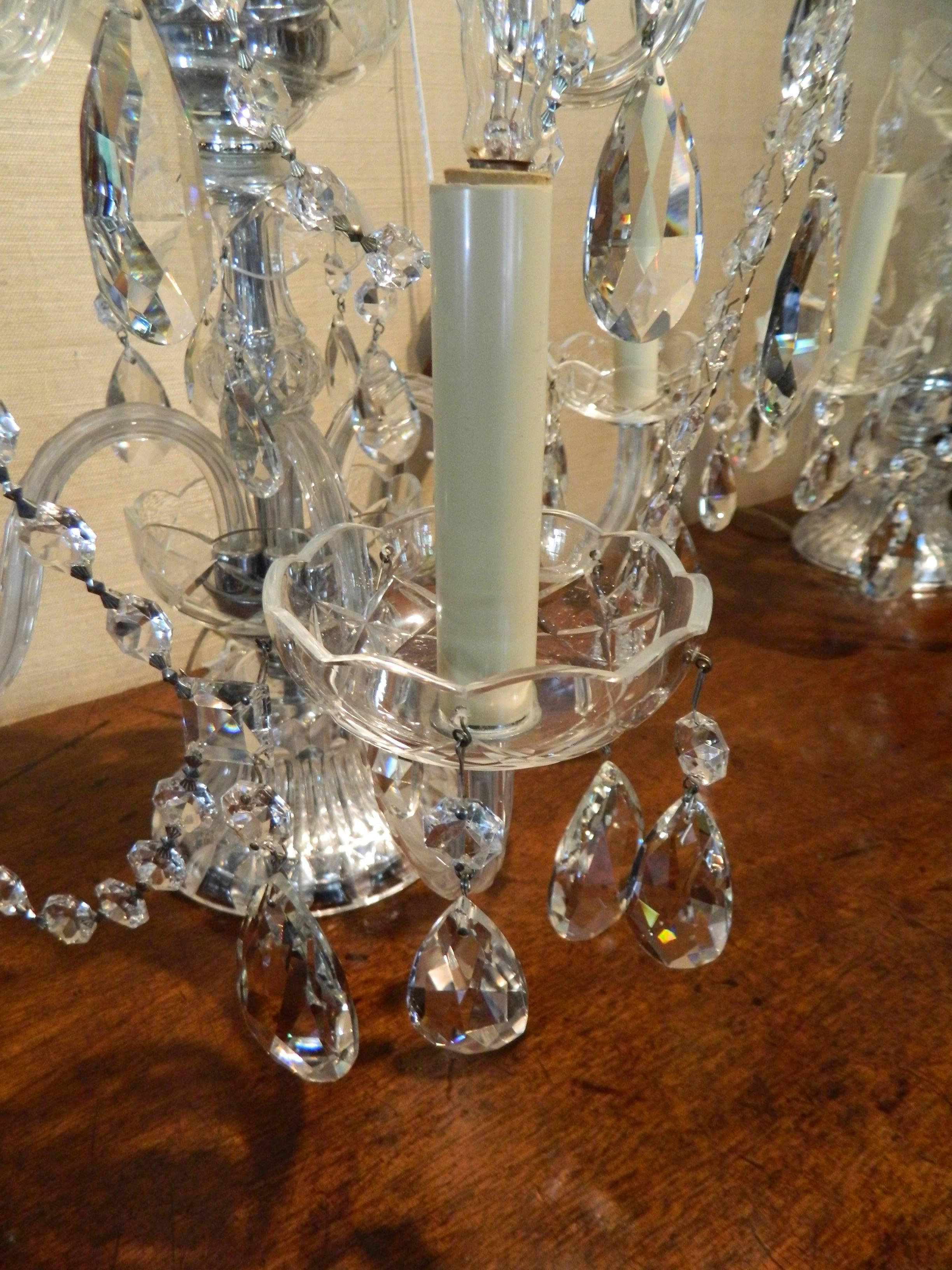 Pair of crystal five branch electrified candelabras with swags, early 20th century. Bottom tier with three candleholders and bobeges and top tier with two candleholders. S arms with swags and crystal drops.
           