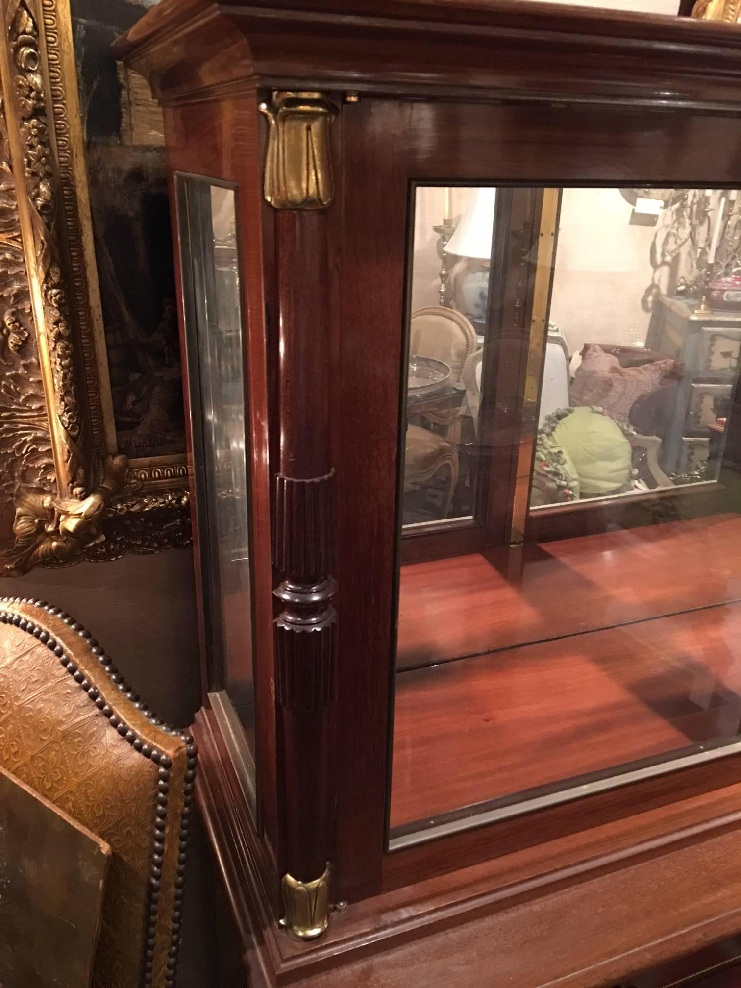 French Directoire Style mahogany cabinet with brass trim decoration and glass doors over wood doors opening to wood shelves, late 19th century.
   
