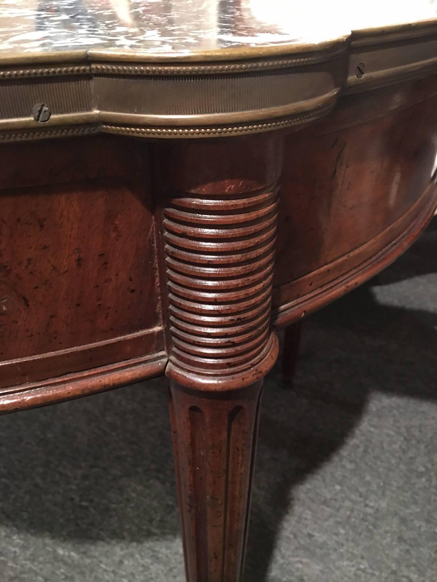 Louis XVI style mahogany and marble top bouillotte table, 19th century. The circular marble top within a full brass trim, above a frieze fitted with two small drawers and two candle slides, raised on fluted, tapering circular legs ending in brass