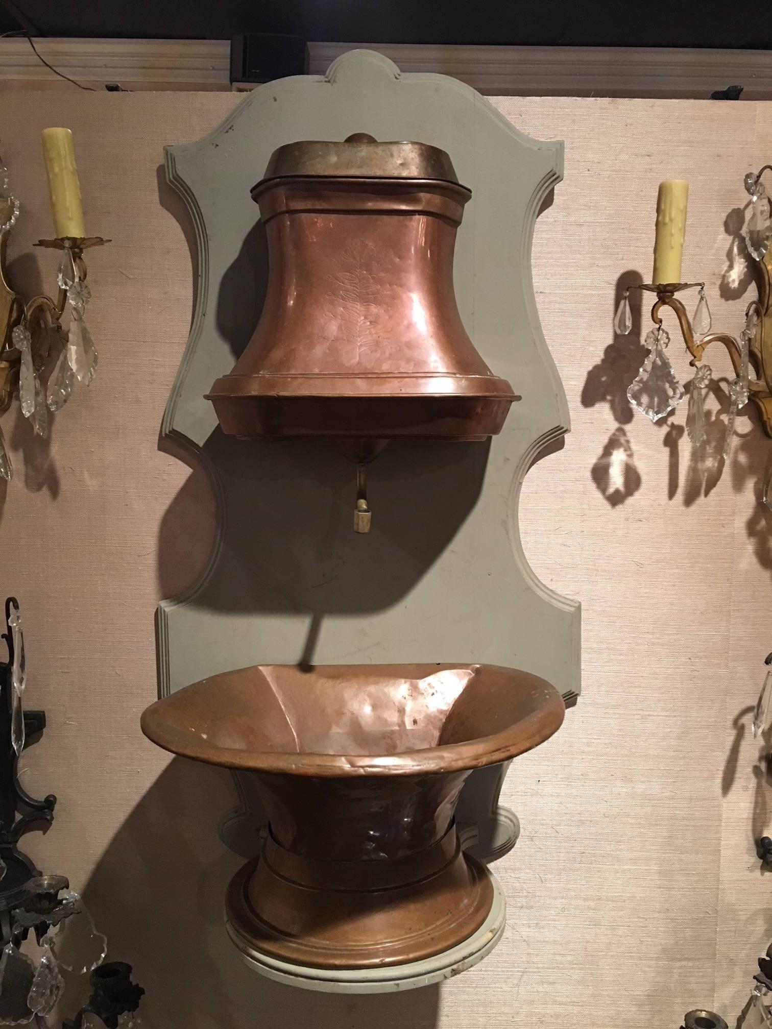 Lavabo francés de cobre del siglo XVIII con detalles de latón sobre tablero posterior.
 