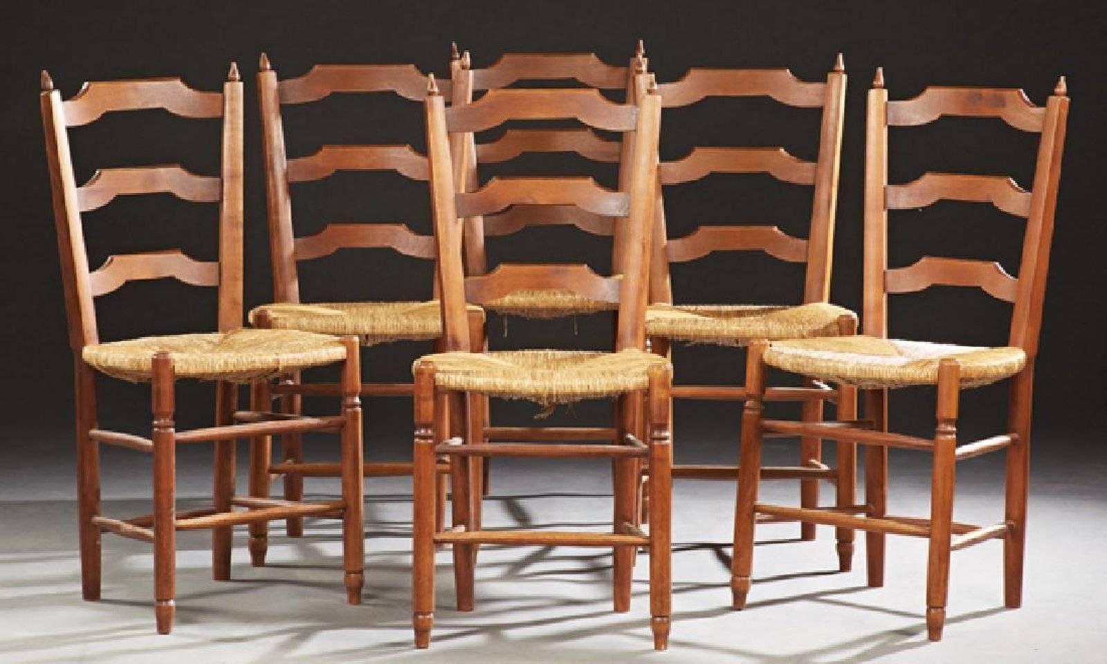 Set of six French Provincial carved cherry rush seat dining chairs, early 20th century, the arched ladder backs within spindle topped stiles, to rush seats, on tapered cylindrical legs joined by tapered stretchers.
 