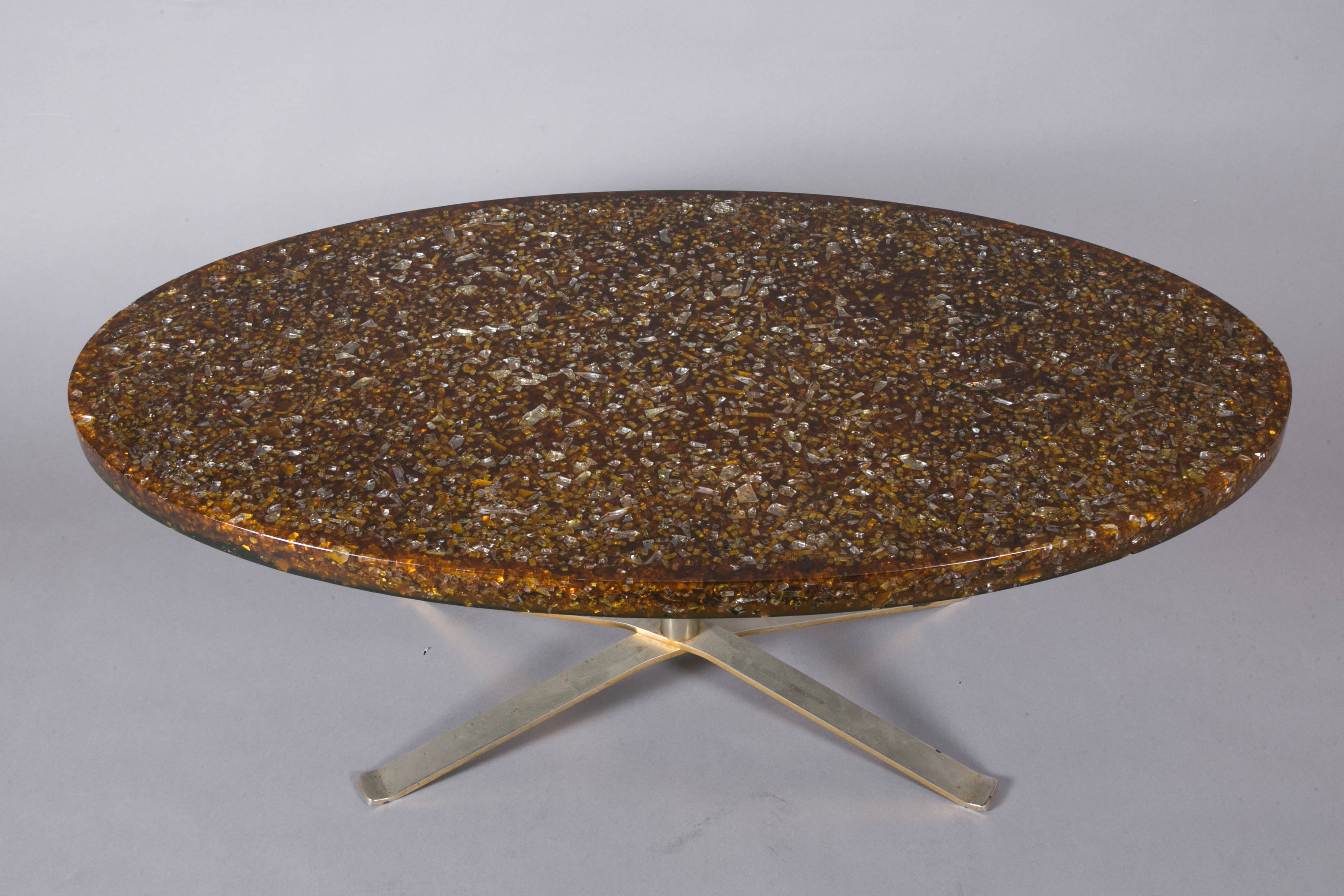 Coffee table with an oval resin top, circa 1970, by Pierre Giraudon (1923- ).
Top in brown translucent resin with several glass inclusions. Four crossed legs stainless steel base.
    