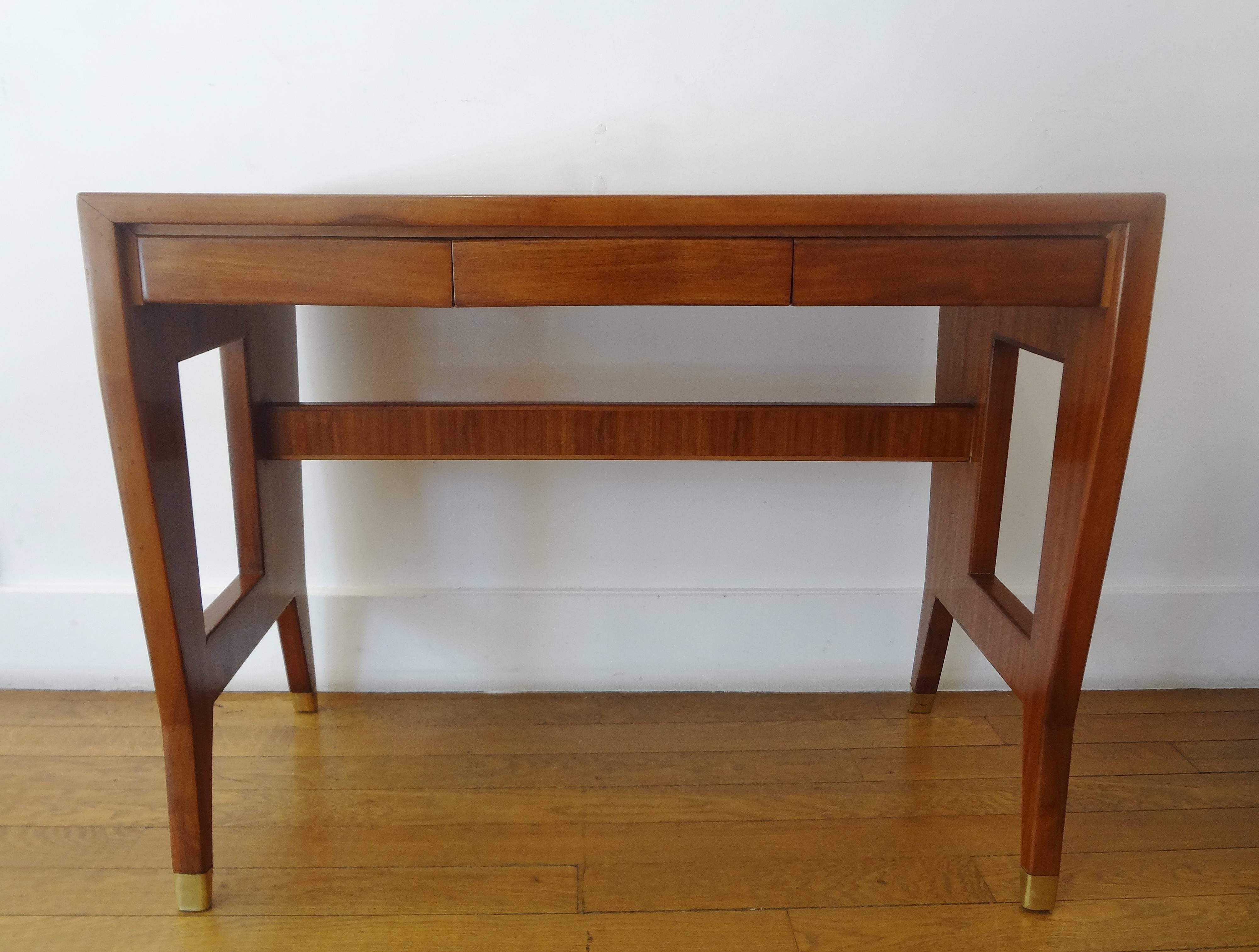 Small rectangular blond mahogany desk, 1955, by Gio Ponti (1891-1979) 
Geometric open sides, with upper cross-bar and gilt brass sabots.
Opening with three front drawers.

Typical wellknown Ponti's designed profile.
Provenance: Part of the