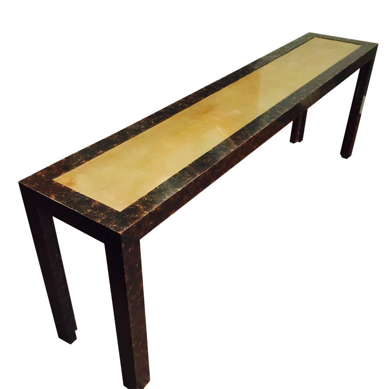 A John Widdicomb long wood console with an antiqued brass top and painted faux tortoise detailing, 70