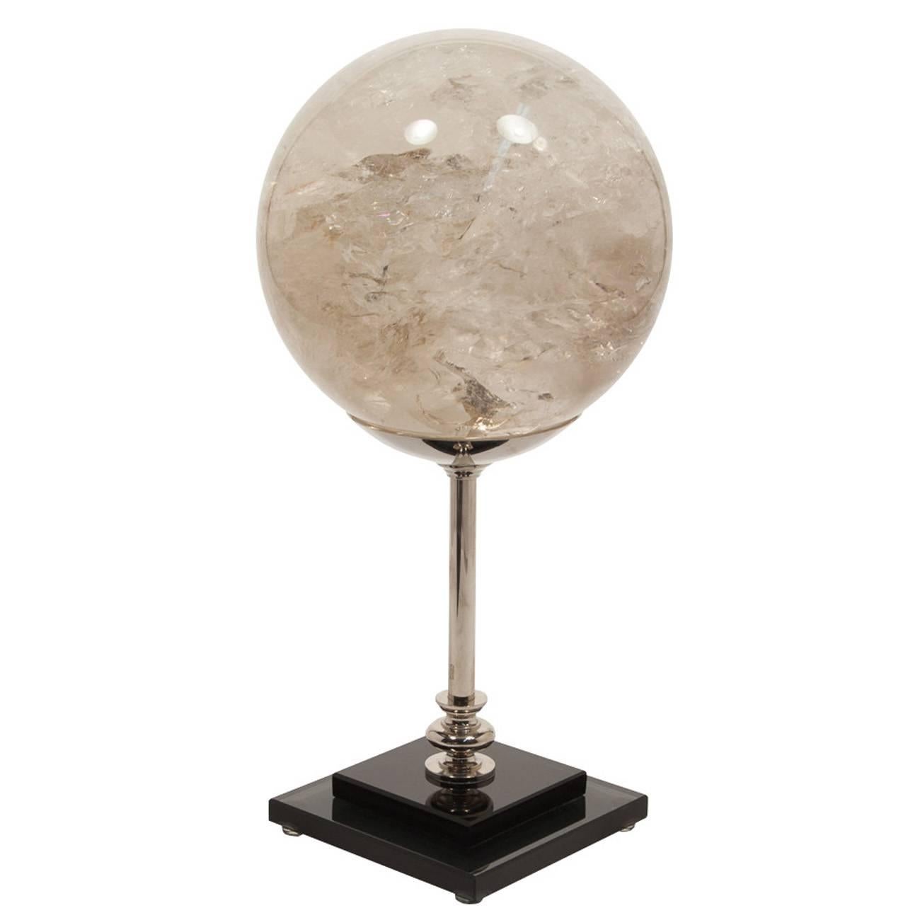 An extra large hand-carved white quartz sphere on a nickel-plated Stand with a black glass base.