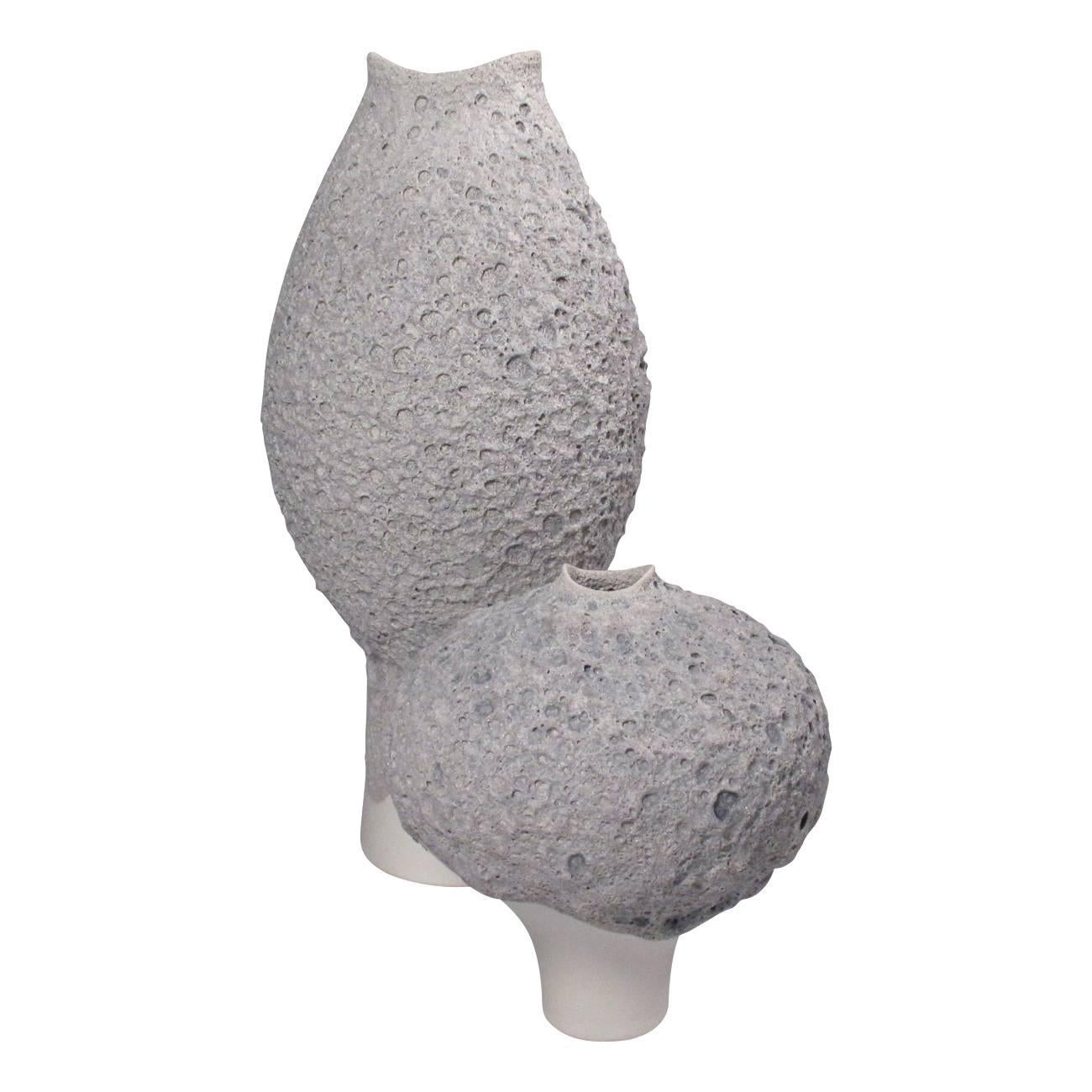 A tall light grey ceramic vase with a lava glaze. Additional items are available in the collection.