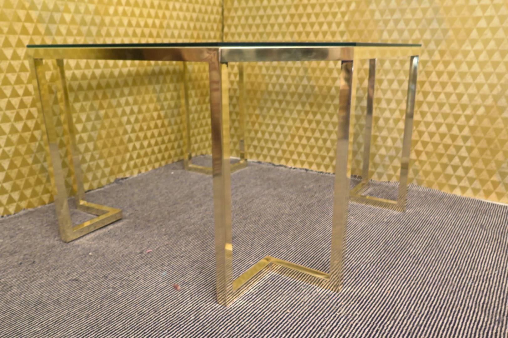 Sofa table from the mid-century. Structure completely in brass with glass top. Its design is a square but with flat corners, forming an irregular octagon. The legs always in brass follow the design of the table top, with feet that enter inside.