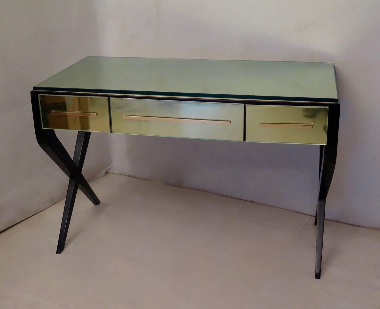 Gorgeous desk or writing table, designed by Gio Ponti.
All in black lacquered wood, with the top and three drawers covered with a polished brass plate, with a monolithic glass over (1.5 cm, 0.6 inches). The central drawer is larger than the two
