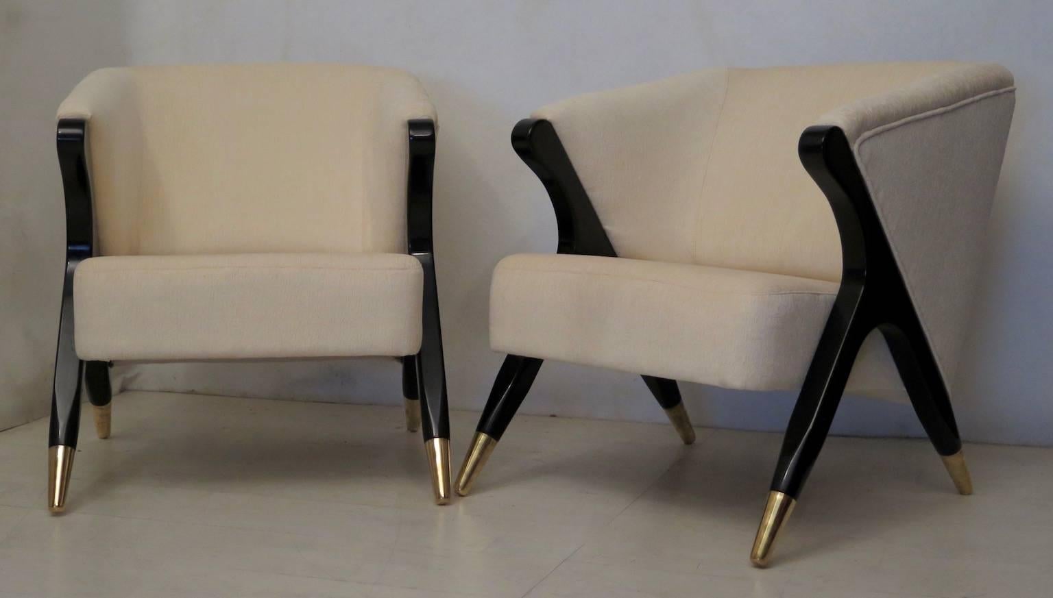 Pair of Art Deco armchairs, covered in white fabric, with black lacquered legs. The feet are made of brass. Particular their shape of an inverted Y.
Comfortable armchairs gathered and enveloping. Beautiful for a living room, or as office chairs.
 