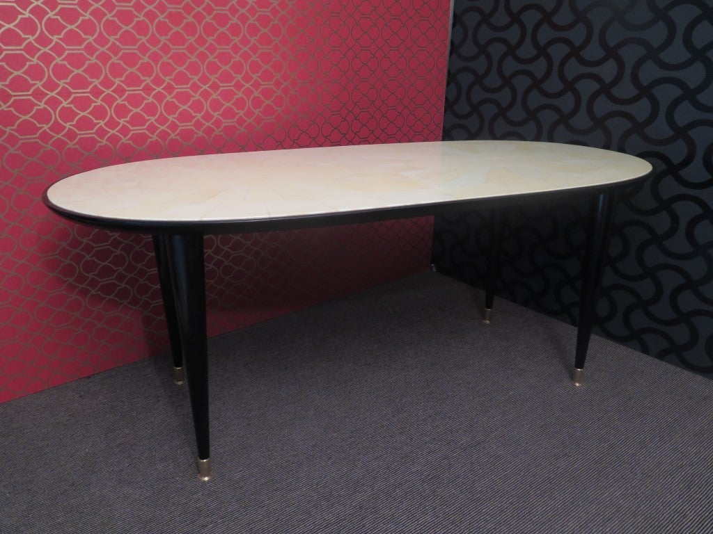 Italian Art Deco table. Linear and essential, in characteristic Italian style of Paolo Buffa, Vittorio Dassi and Osvaldo Borsani.

Top all covered in parchment leather or goat skin with large edge in black lacquered wood. Note the design that forms