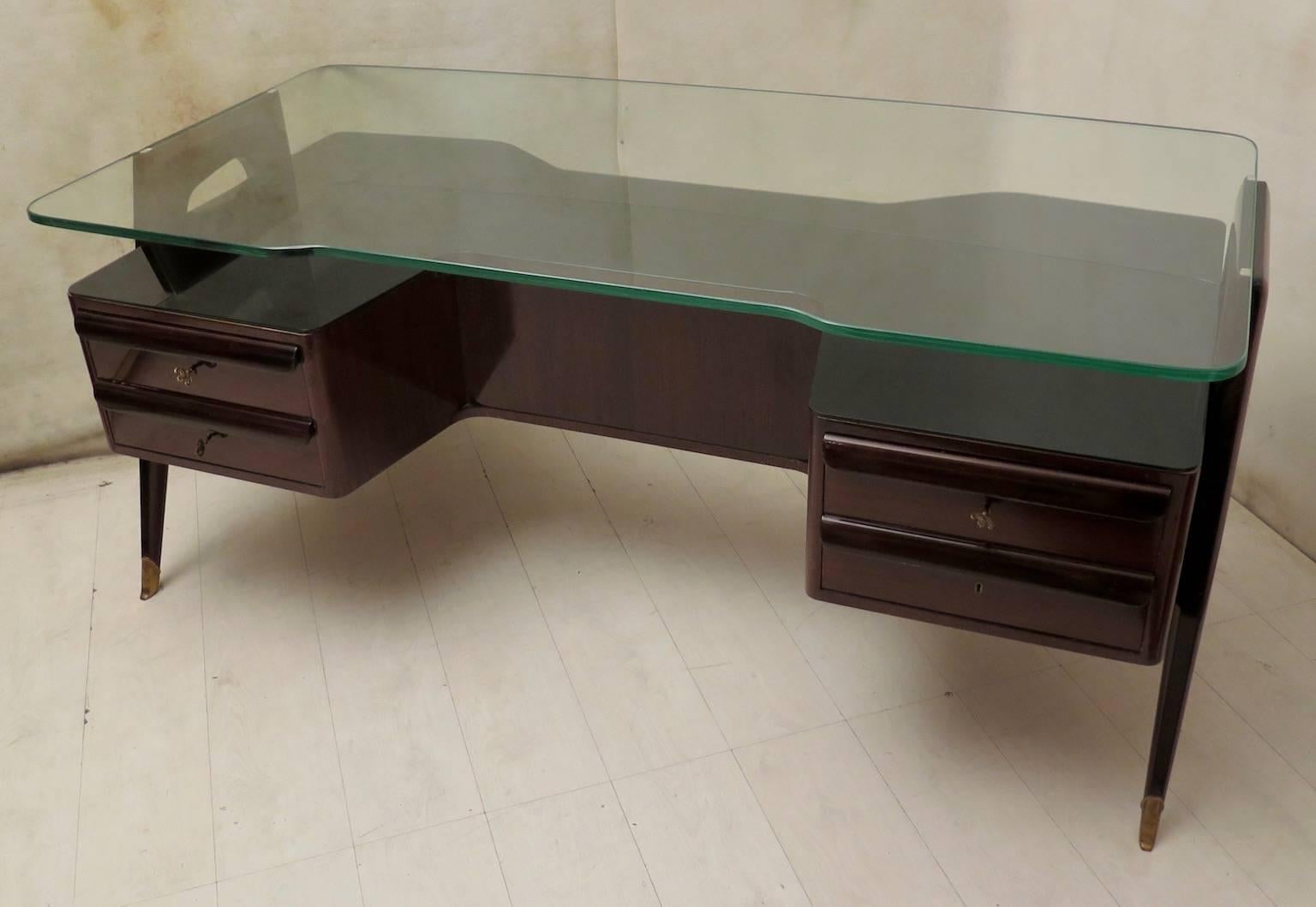 Desk well articulated in its design, beautiful collector's item. Desk from the mid-20th century of Vittorio Dassi. 

All veneered in walnut wood, surmounted by a large piece of monolithic glass. Composed of a body with four drawers, two on the right
