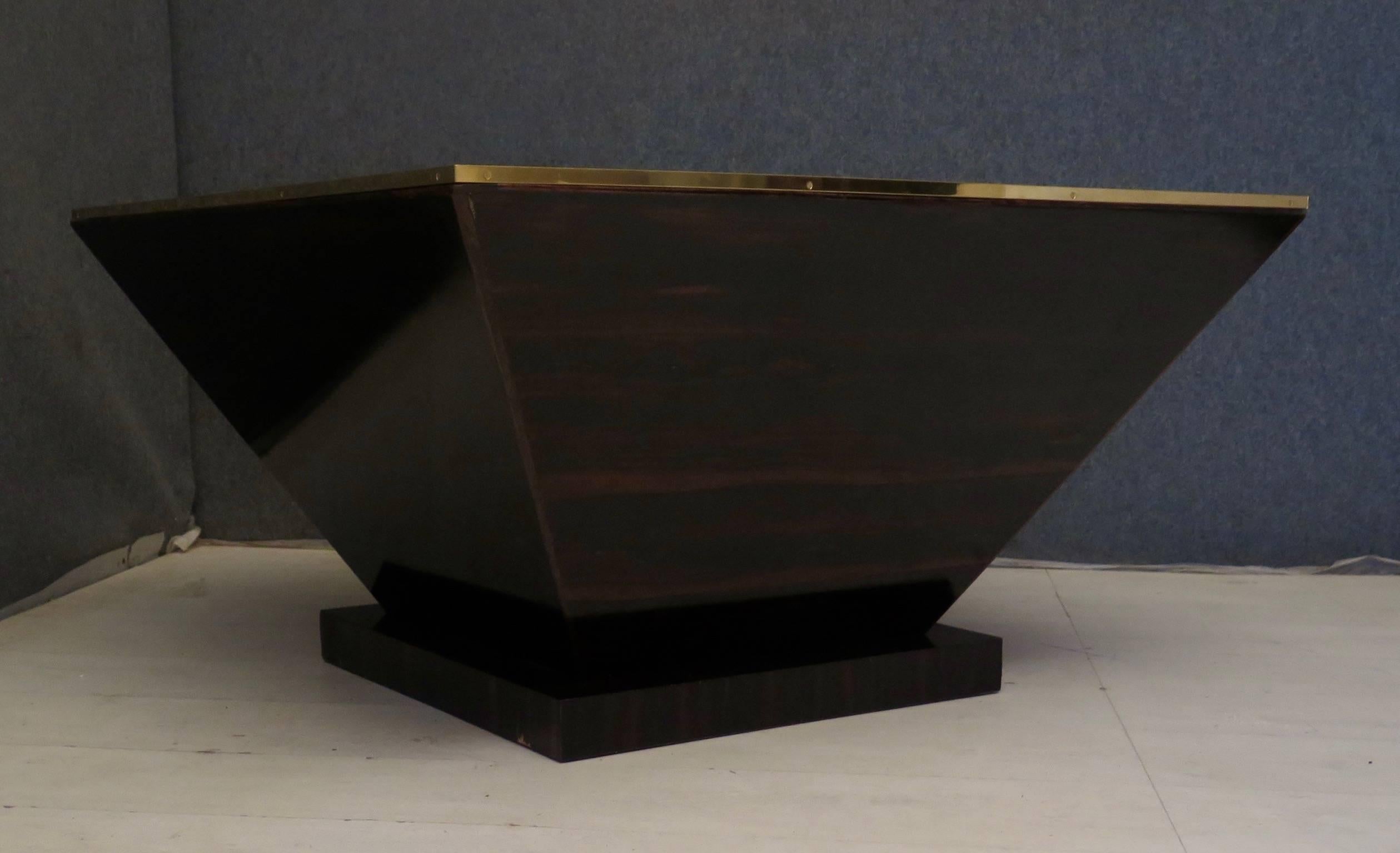 These perfectly smooth walls, and the sharp angles, of the inverted pyramid of its design, make the sofa table like a real sculpture, accentuated by the fine brass edge.

Square-shaped, the wooden structure of the table is completely covered with