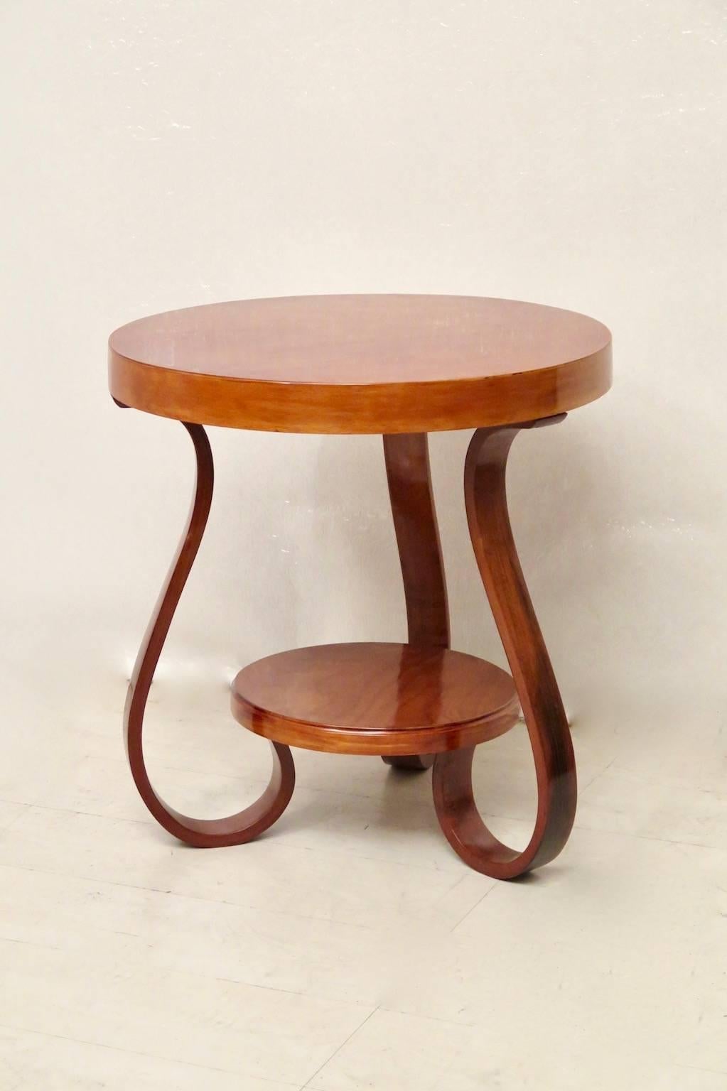 Very classic Art Deco curved wooden side table.

Of round shape and veneered cherrywood top, with a band that runs all around. Under the top, there are three legs bent by steam. These are held together by a cherrywood top, placed underneath. The