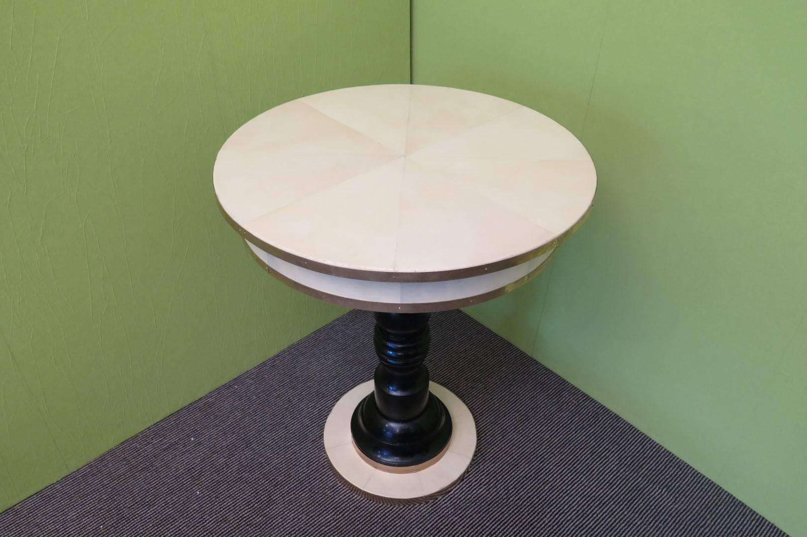 Italian Art Deco side table. Top covered in parchment leather and edged with a brass band. Even the band below the top is covered in parchment leather and finished with brass. The legs are single and central is polished in black lacquer. This is