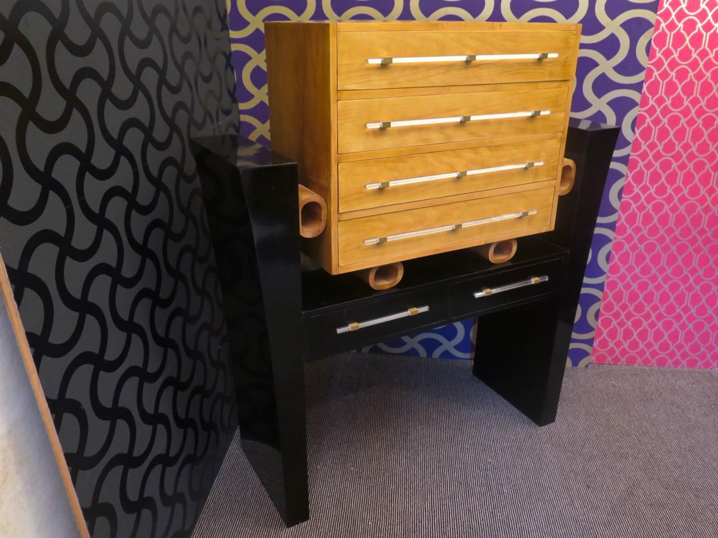 Chest of drawers of the Italian school of Art Deco. Made of two parts, a top one entirely covered in maple wood, with four drawers, and the other lower, foot, polished in black lacquer. The two parts are separated by four wooden rings, which