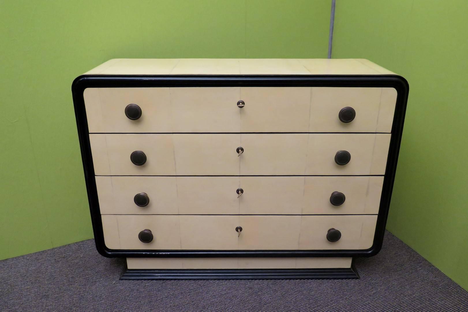 Italian art deco dresser. All covered in parchment leather, both the body and the drawers. The four drawers all around have a wooden edge polished in black lacquer. The drawers can be opened by means of two brass knobs and a central key. The whole