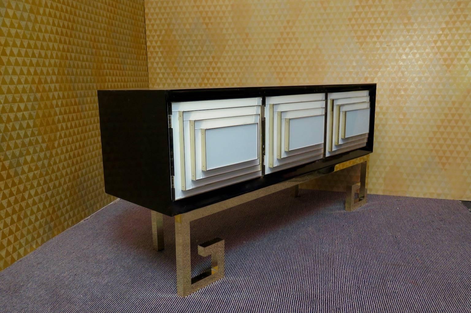 Truly unusual this hutch buffet, all black body with three doors covered in white glass and brass, to note the design of the doors as a truncated pyramid. The too much special leg is made of brass.
Only 71cm high, 28 inches.