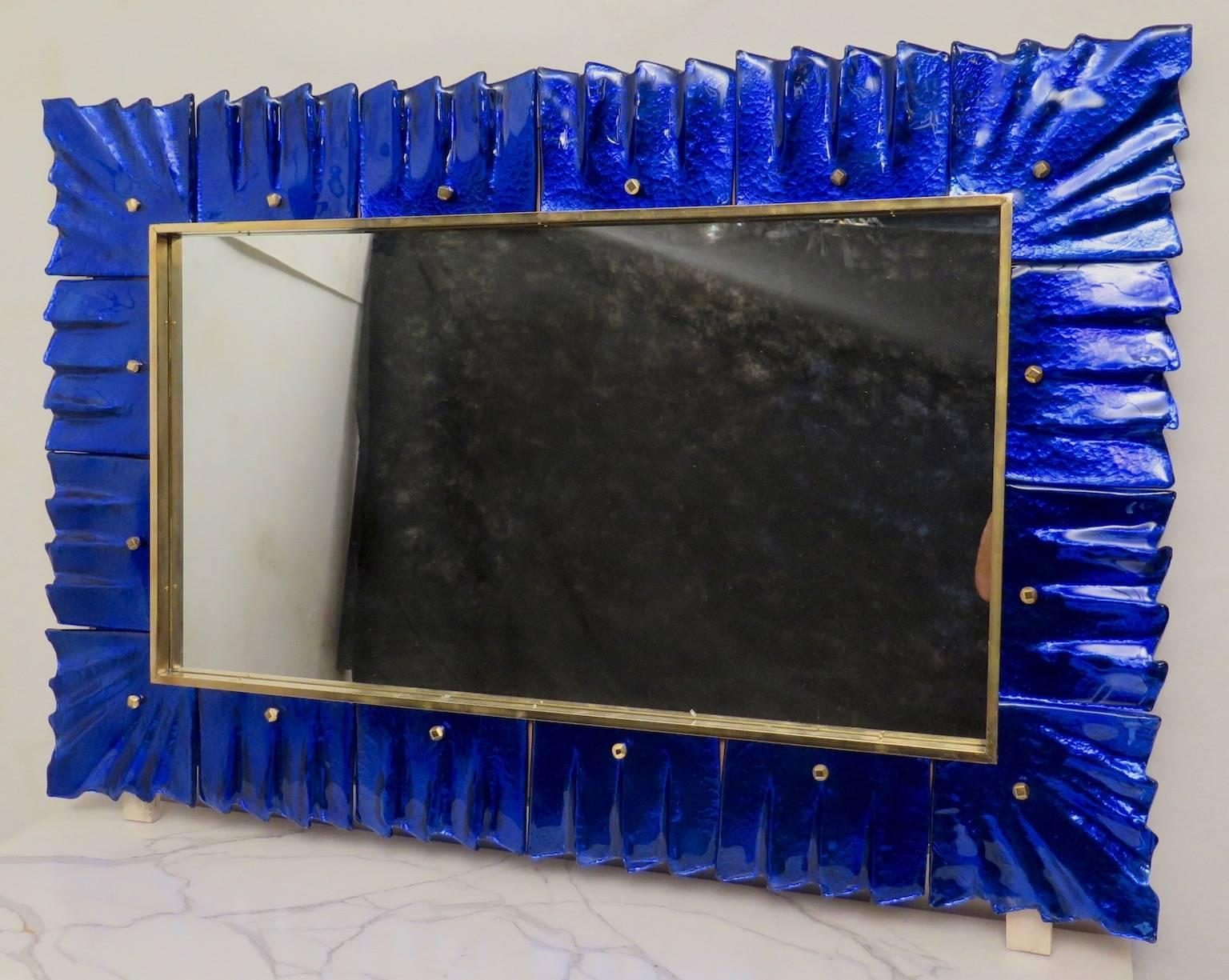 Mirror with Murano glass frame, consisting of several pieces of blue art glass,
with buttons and brass interior trim. Item very special and unique in its style. Very particular glass processing of color blue but silver behind, so as to give a