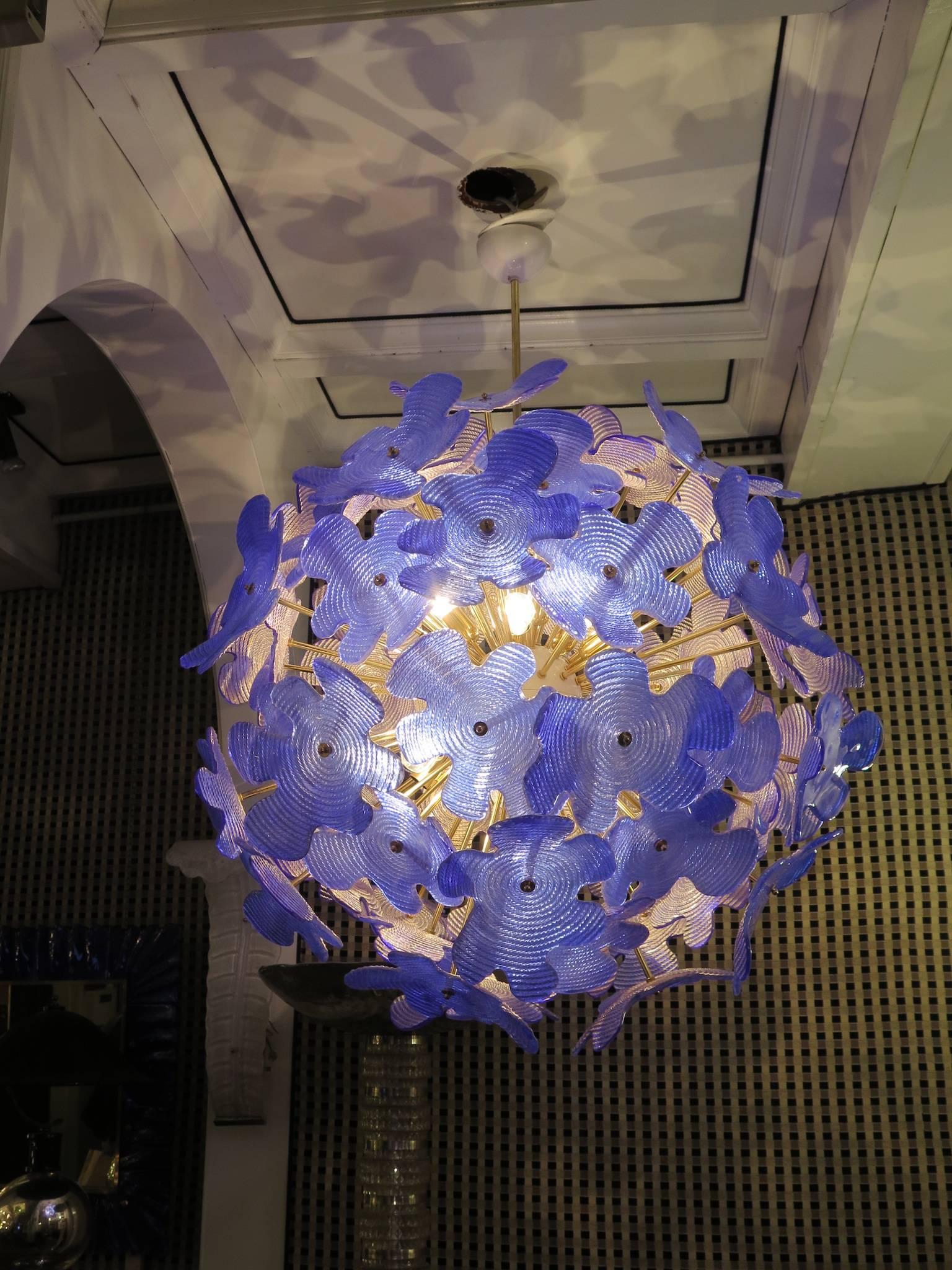 The large glass flowers make up this Murano chandelier from the 1970. A classic Sputnik from the middle of the century.

Made of a large central sphere in which brass rods are screwed, glass leaves are placed above the brass rods. It has 18-light
