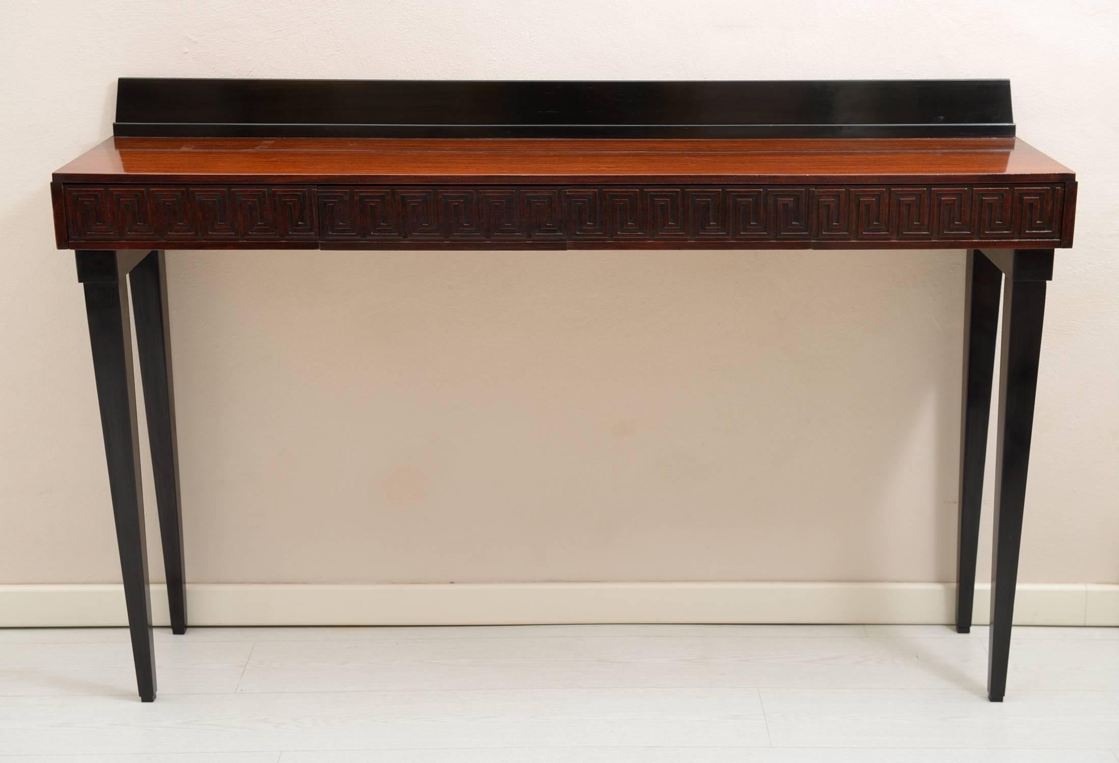 Rosewood and black lacquered console with four drawers with carved Greek decoration, slender legs.