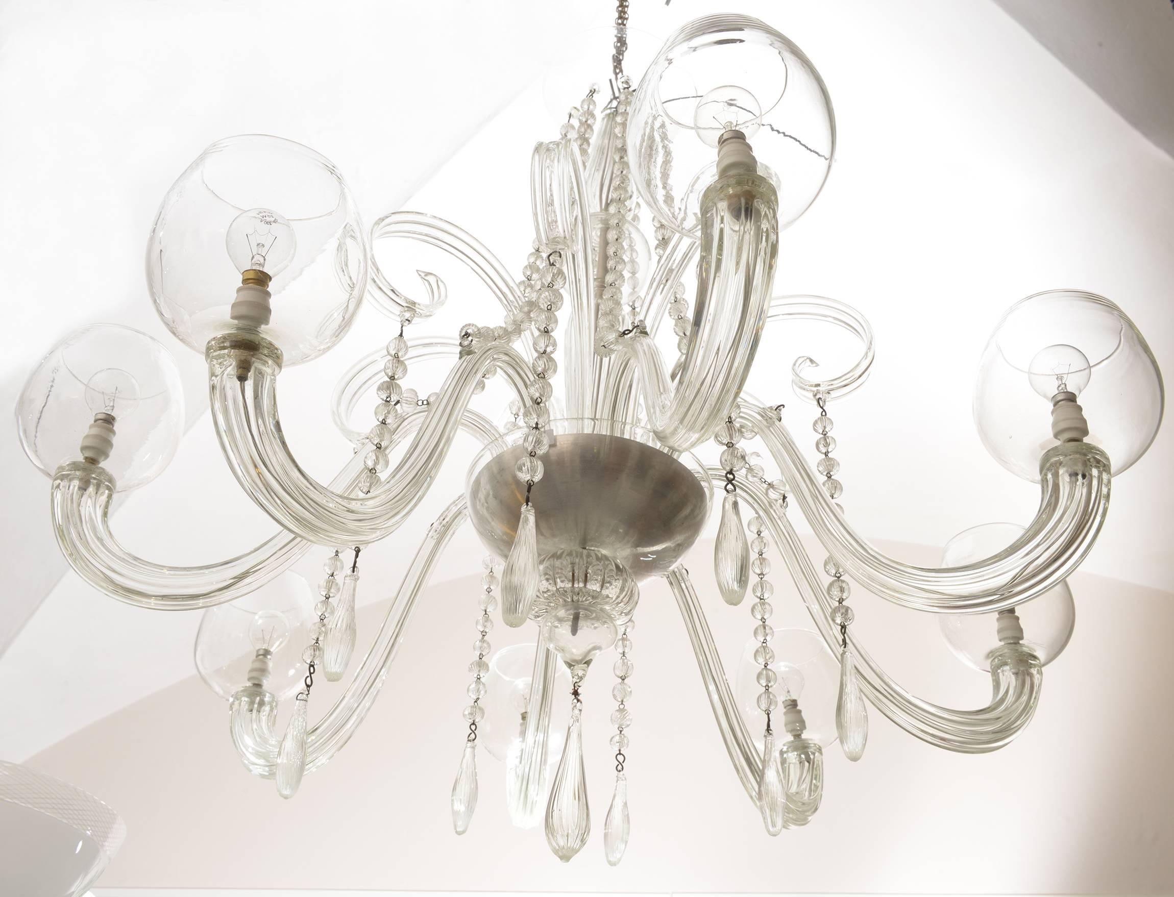 Elegant chandelier with eight arms and lights, glass chains and large and long glass drops.