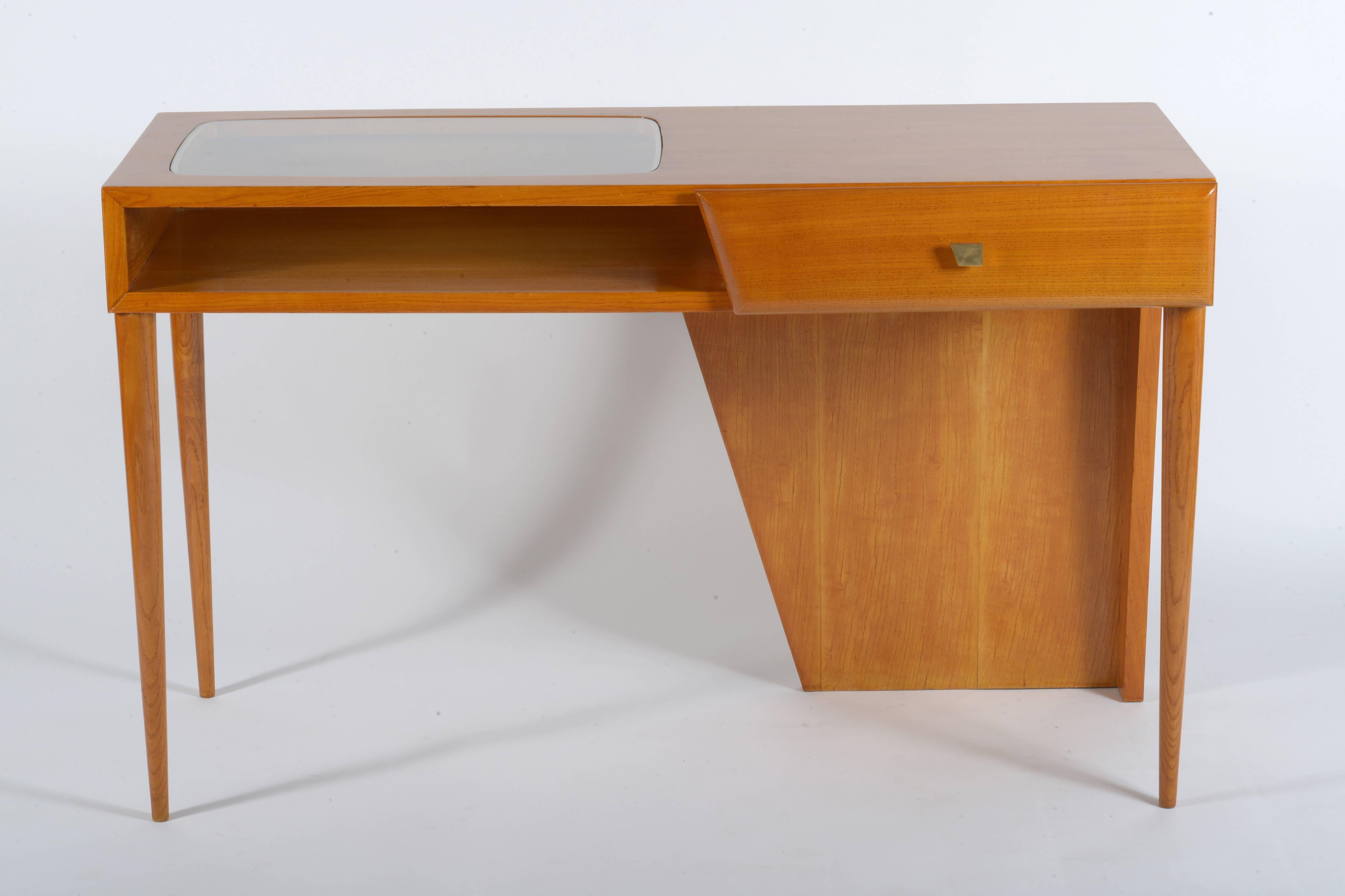 Wall desk in cherrywood with cast brass handle. Oval encased in glass.
Conical slender legs.
The desk should be leaning against the wall, behind a sofa, is not finished behind.