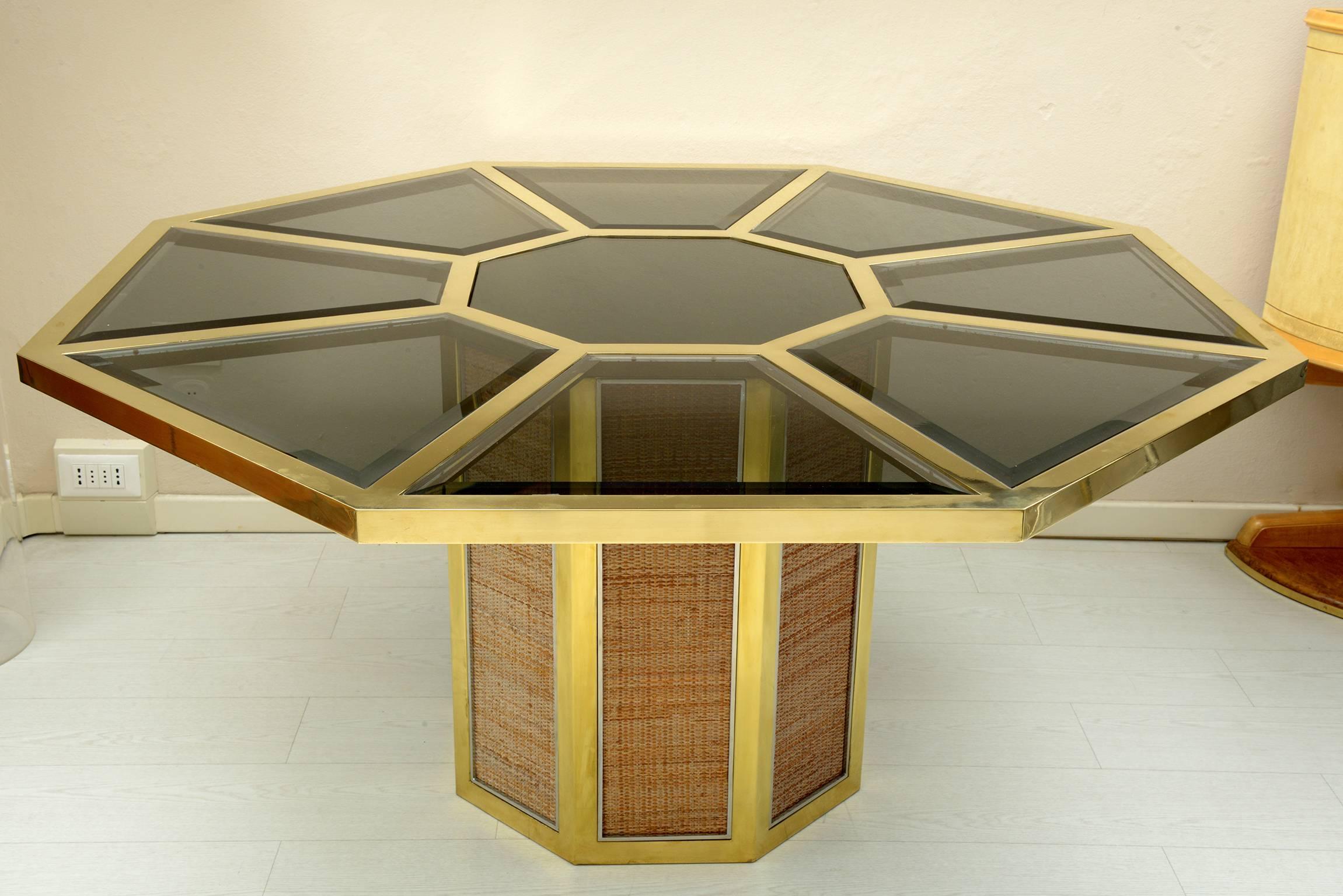 Octagonal dining table or center table with brass frame and chrome-plated brass details. In the center is recessed a Fumè colored octagonal mirror. The top of the eight sides are in beveled fumè colored glass. The eight sides of the base are