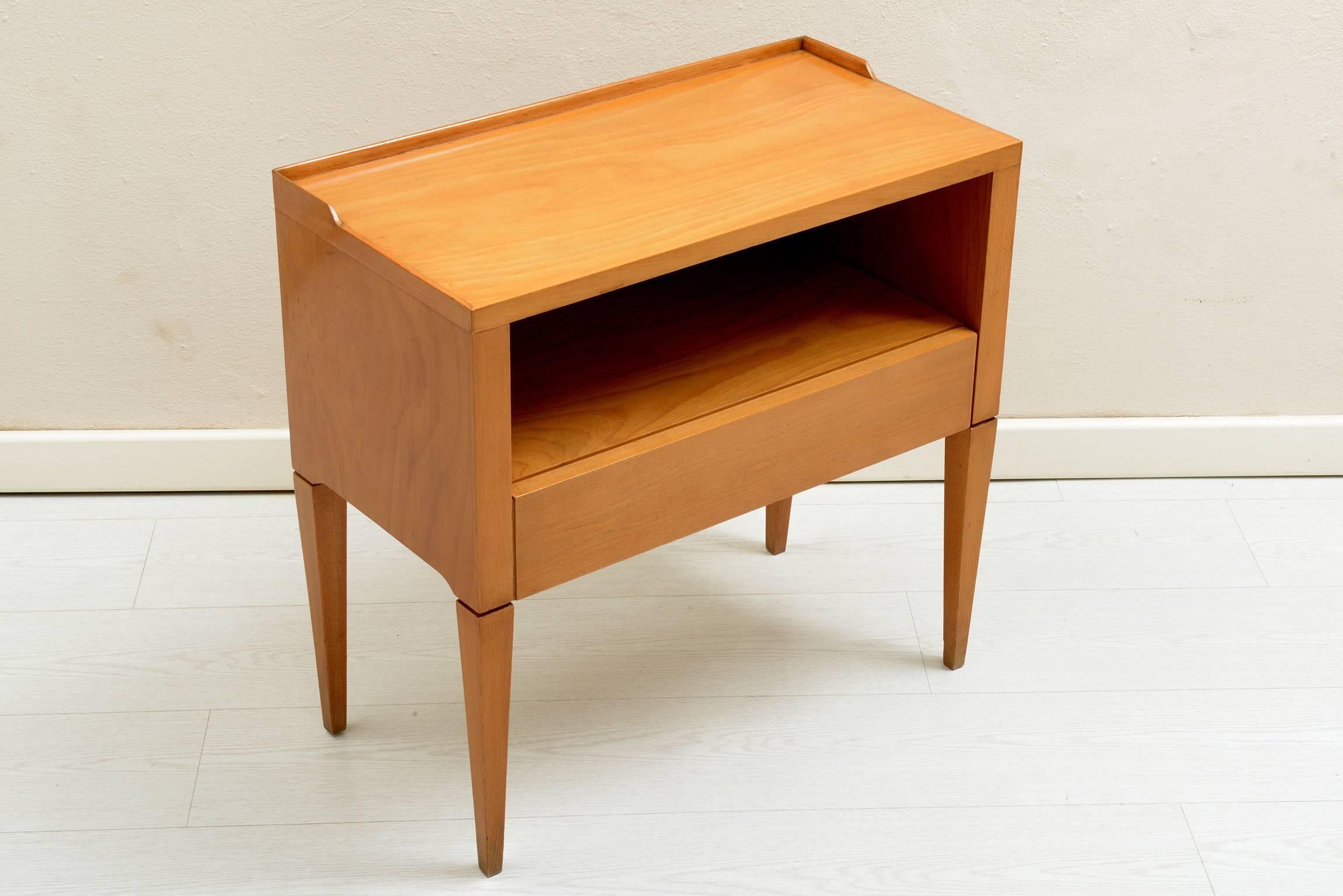 Four tapered slender legs and a drawer under a space to put books or newspapers.