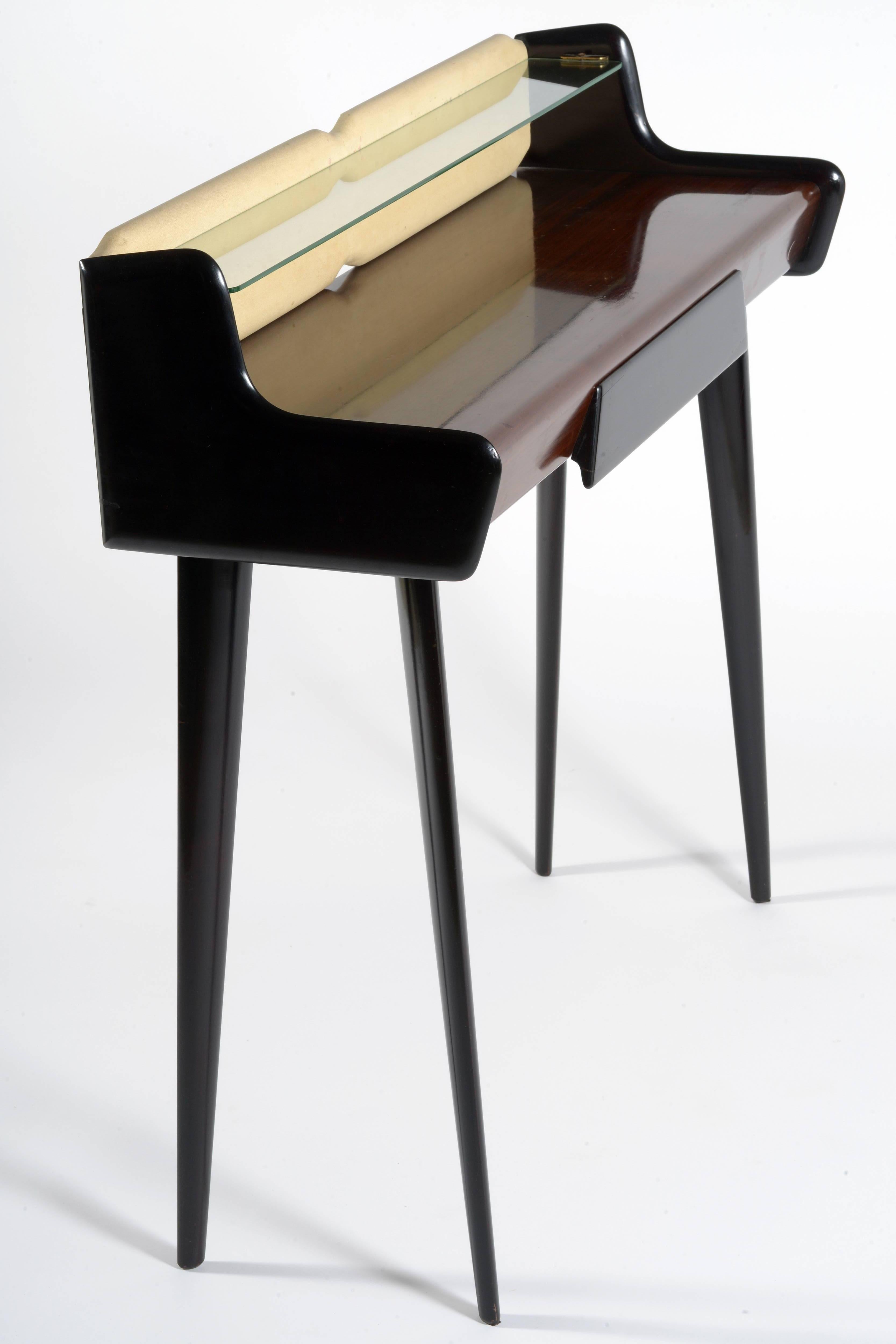 Italian 1950s console, black laquered slender end elegant legs and drawer.
One glass shelf supported by brass details.
The beige part is a panel covered with faux leather.