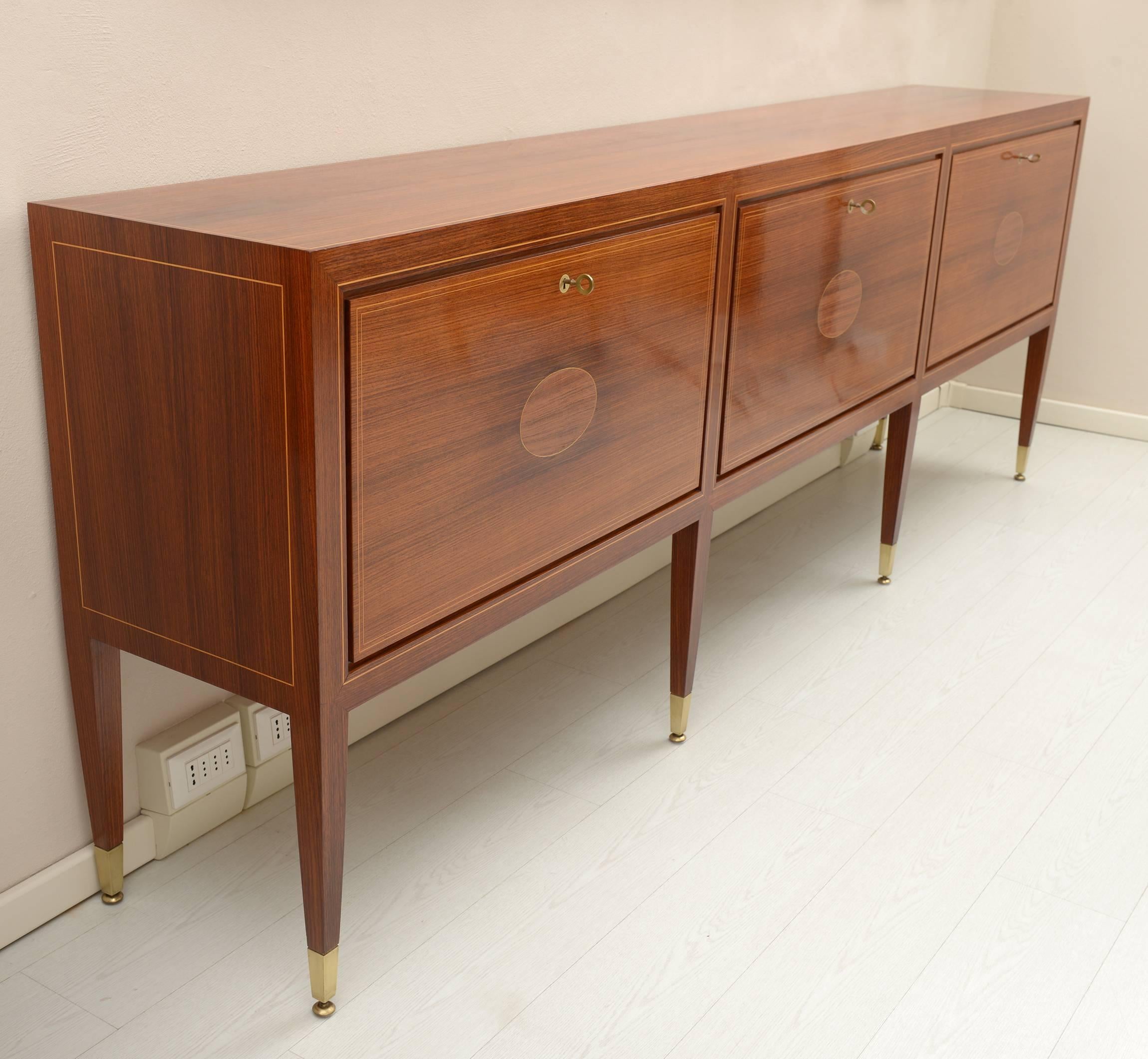 Important and elegant rosewood sideboard inlaid with maple fillets, cast brass feet adjustable through screw, brass locks vents and keys.
 The interior of the three folding doors are made on maple and walnut inlaid.
Designed in 1939 by Paolo Buffa