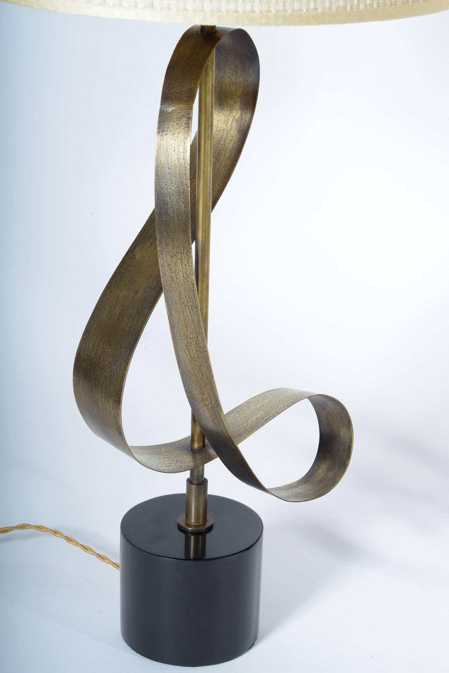 Solid black Belgian marble base and strips in the form of sinuous knurled brass flake.
The brass surface is engraved, knurled, to create a vibrating effect with the light on.
The lamps are shaped like a right and left as a real pair.
The