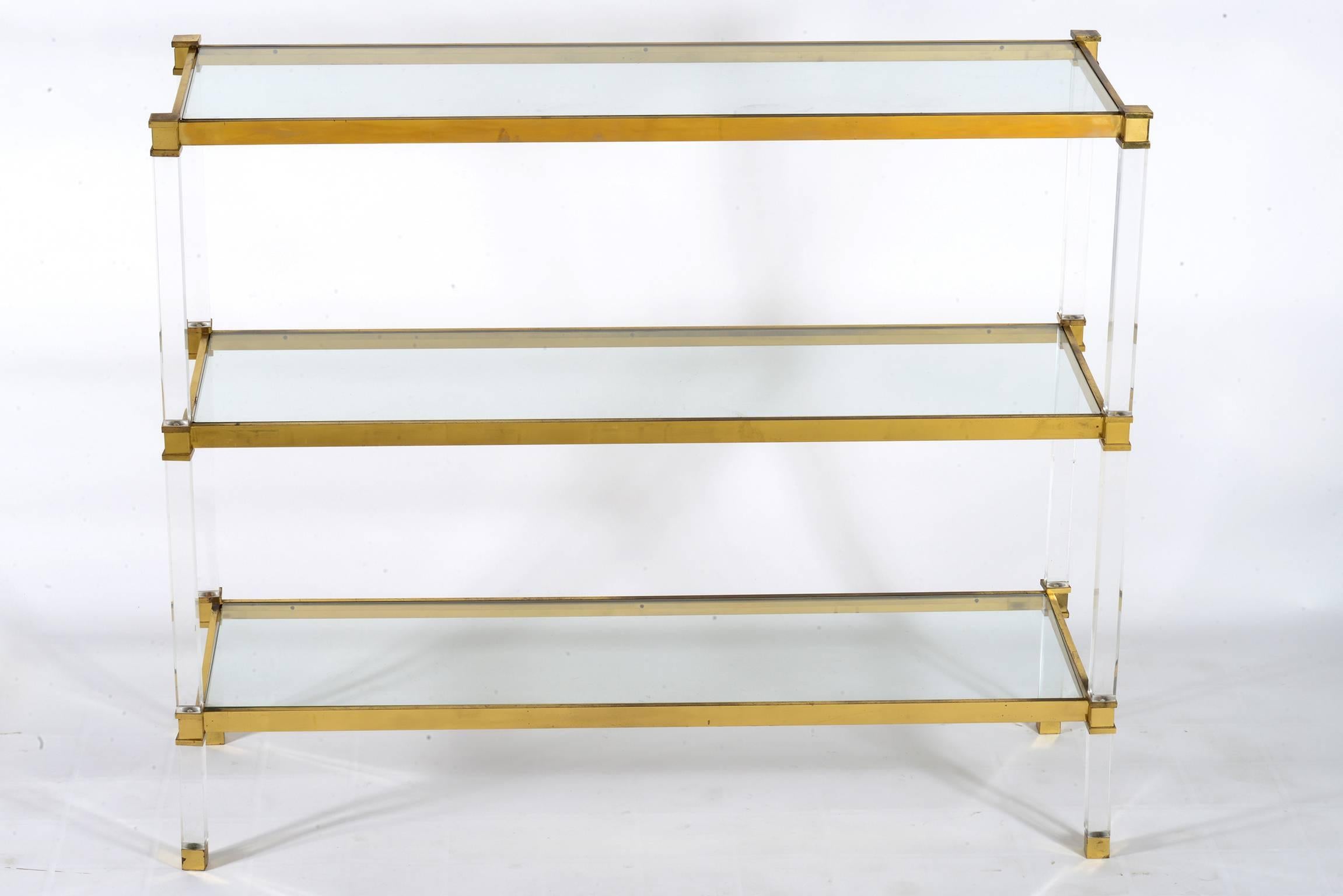 Shelf-console with three glass shelves supported by a Lucite and brass structure.