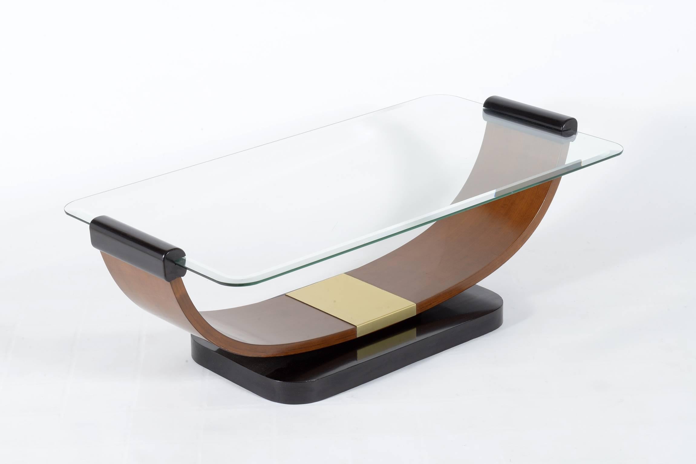 Coffee table with base in black wood with a wooden U on it which supports a thick rectangular glass top with rounded corners and a profoundly ground edge. Brass details on the centre of the wood U.