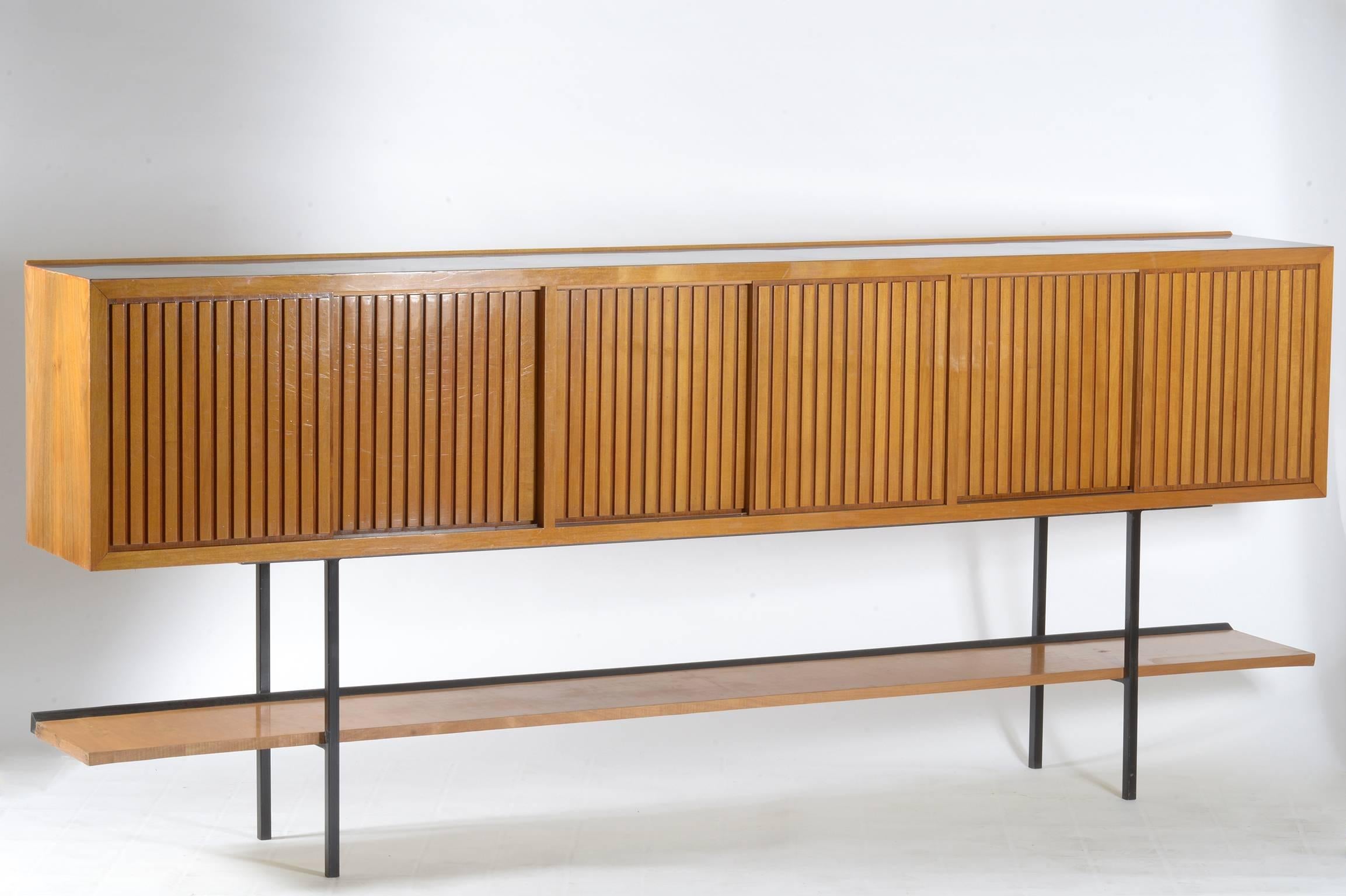 Italian midcentury sideboard with black metal structure legs and black top, six solid walnut grooved sliding doors with big shelve below.
This piece of furniture is not really deep.


 